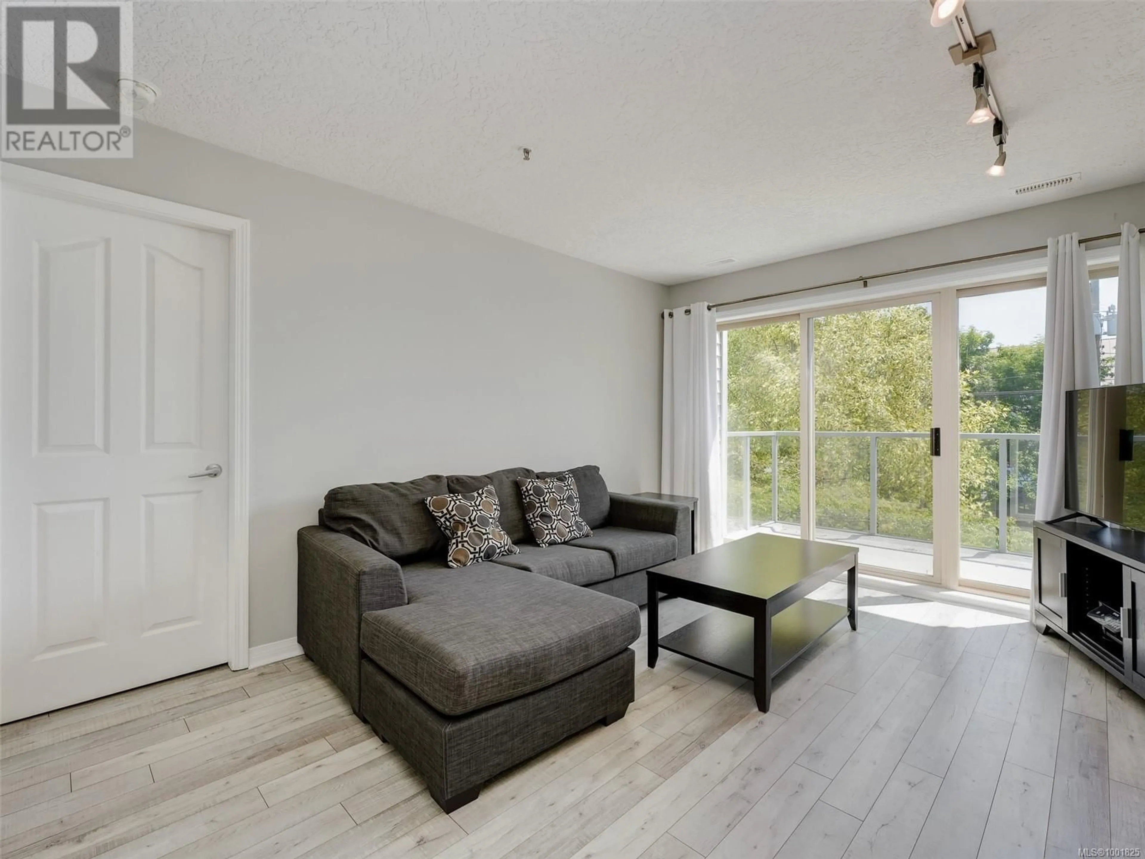 Living room with furniture, wood/laminate floor for 407 - 3160 ALBINA STREET, Saanich British Columbia V9A1Z5