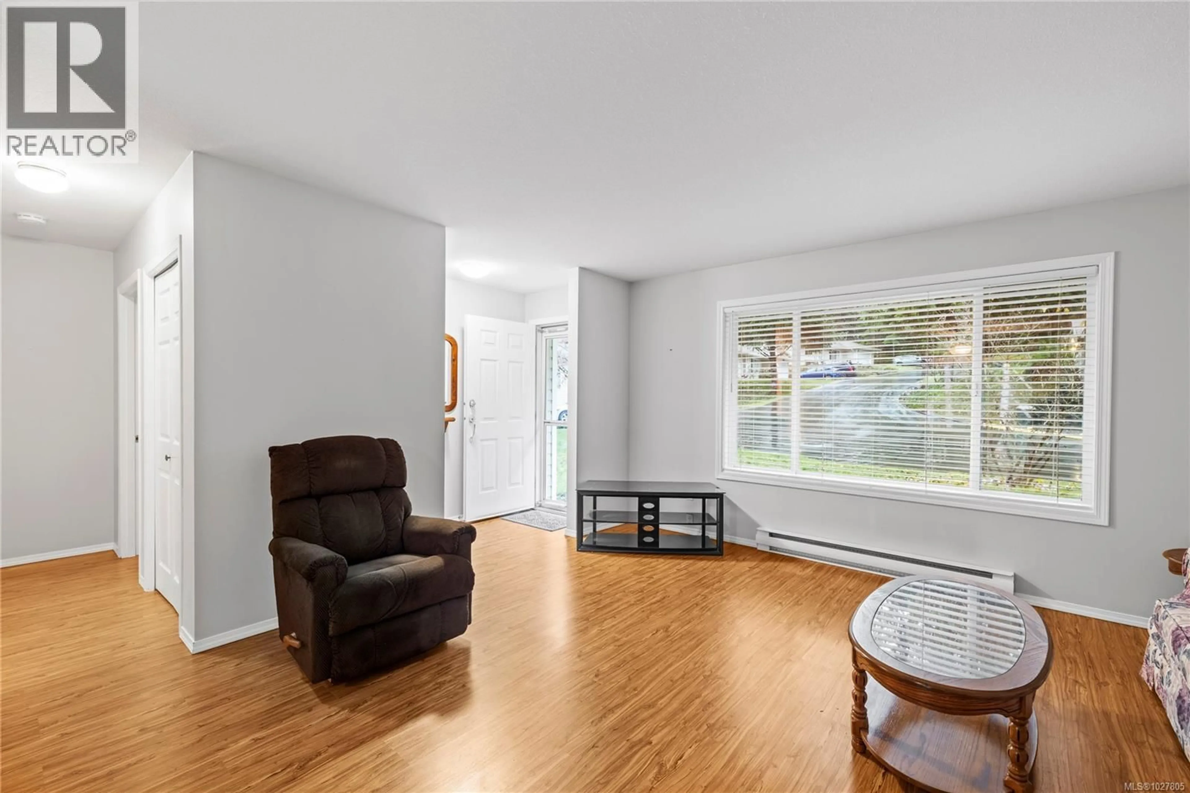 Living room with furniture, wood/laminate floor for 107 - 3105 RINVOLD ROAD, Hilliers British Columbia V9K2R7