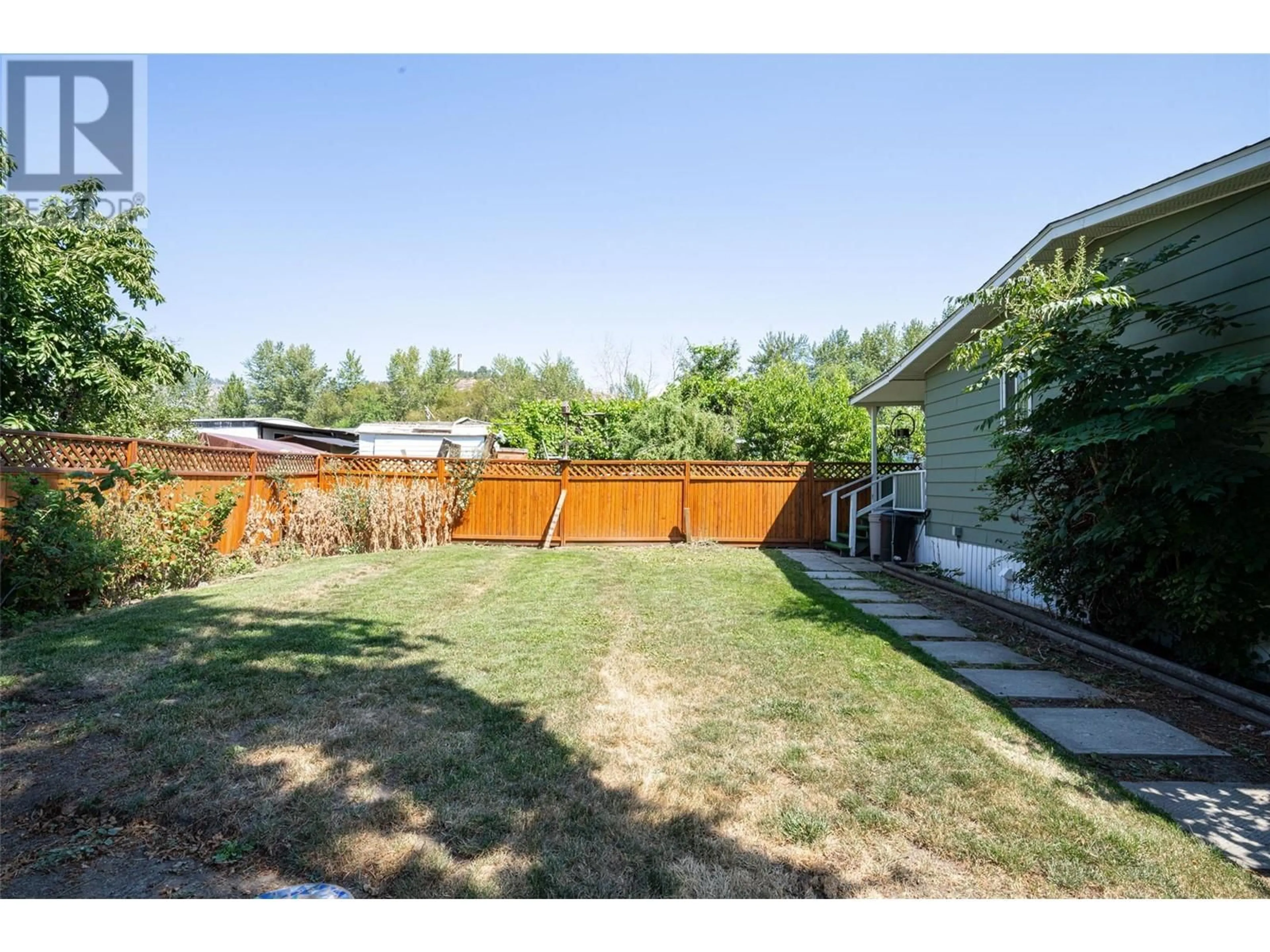 Frontside or backside of a home, the fenced backyard for 1881 Boucherie Road Unit# 49, West Kelowna British Columbia V4T0C9