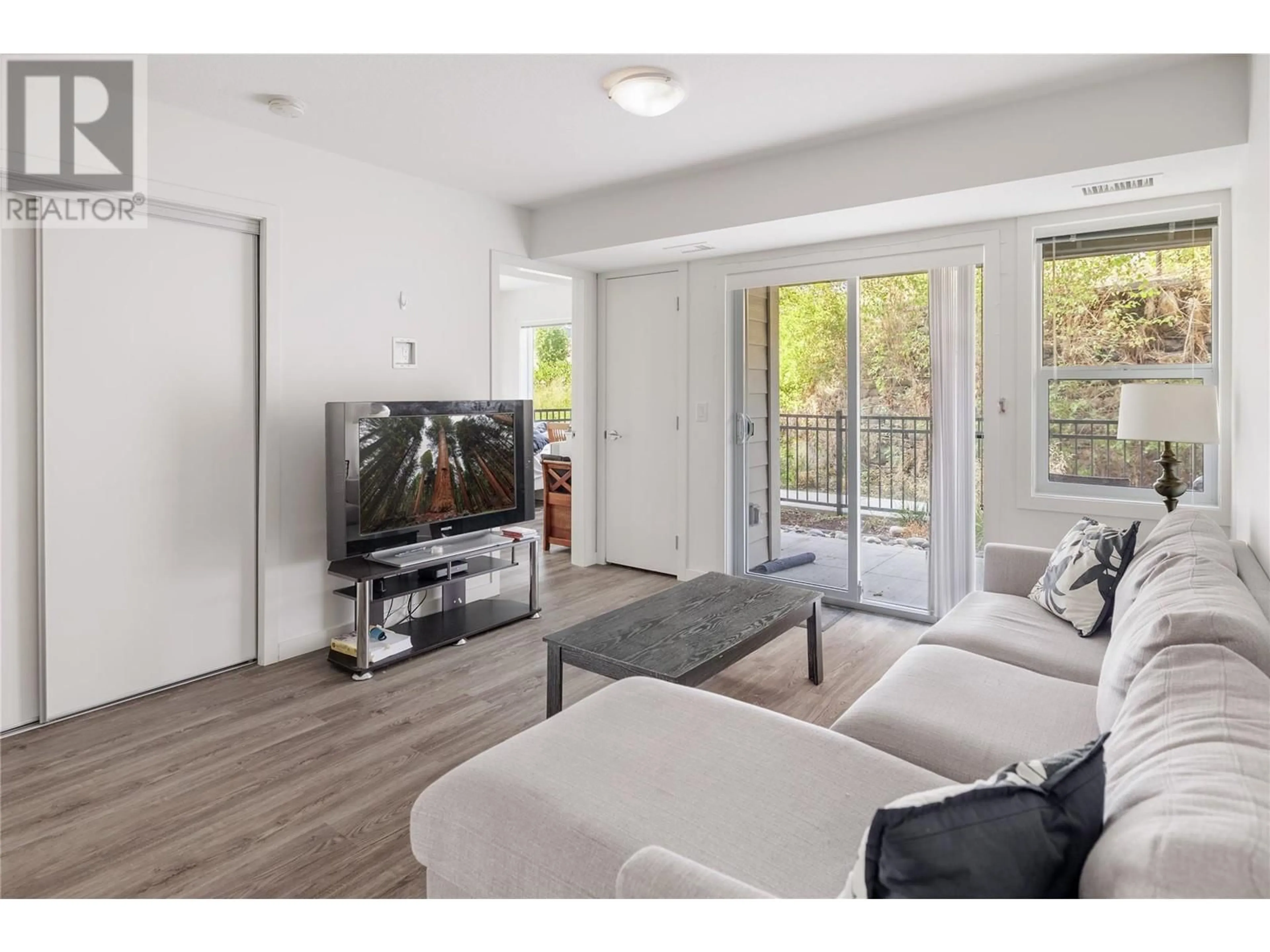 Living room with furniture, wood/laminate floor for 655 Academy Way Unit# 107, Kelowna British Columbia V1V0C8