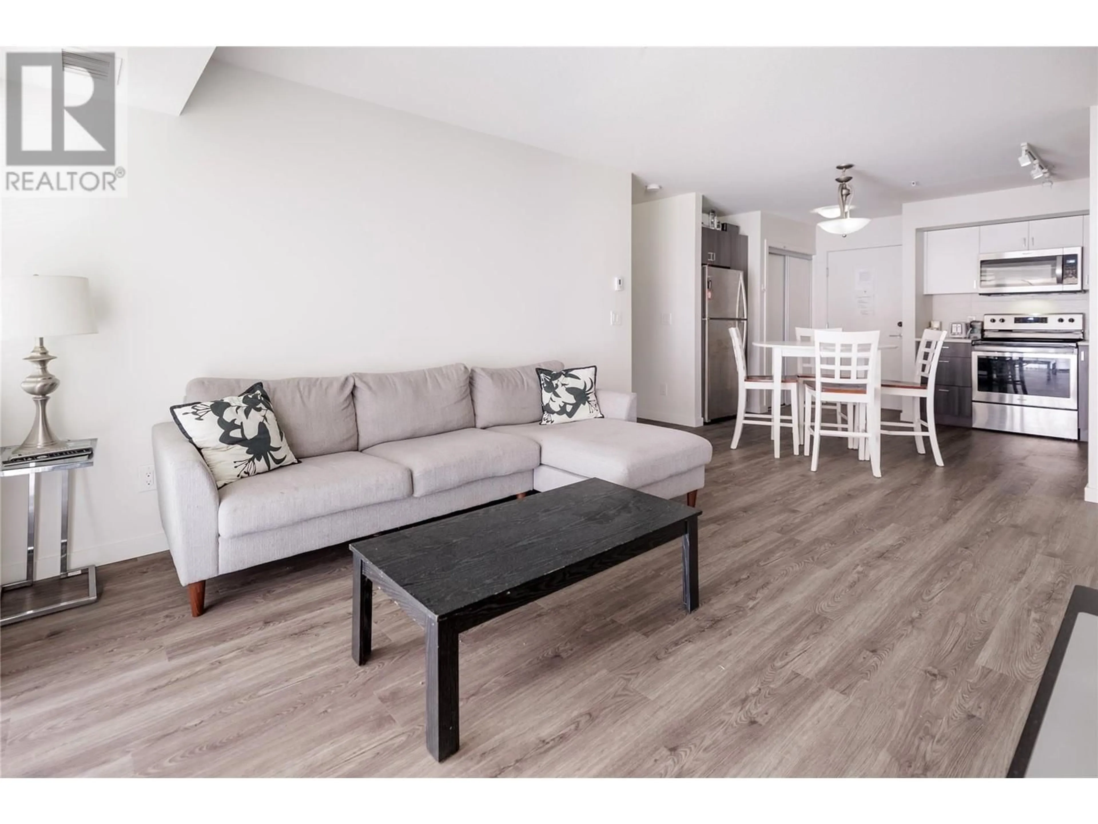 Living room with furniture, wood/laminate floor for 655 Academy Way Unit# 107, Kelowna British Columbia V1V0C8