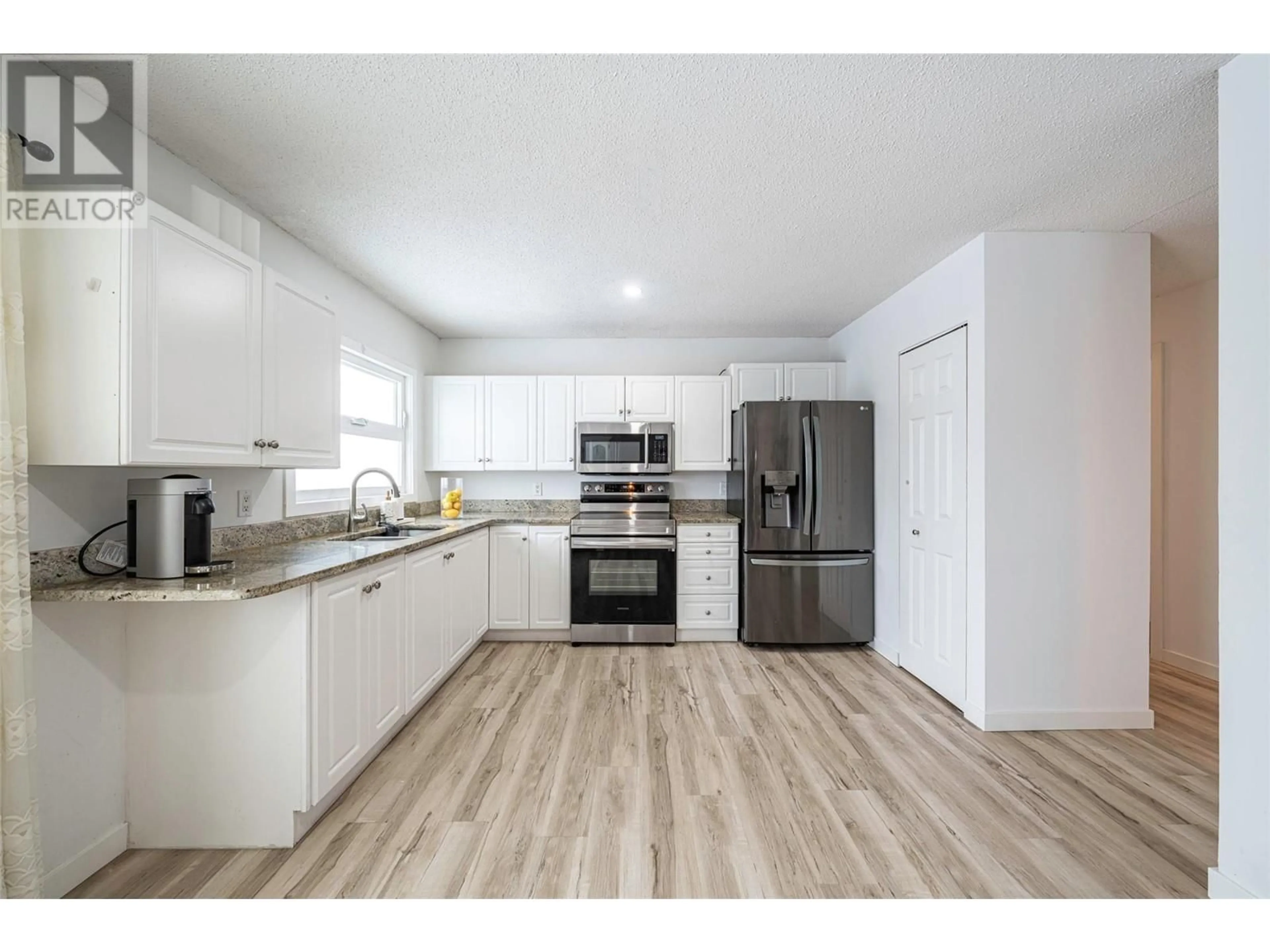 Open concept kitchen, wood/laminate floor for 2412 Butt Road, West Kelowna British Columbia V4T1N7