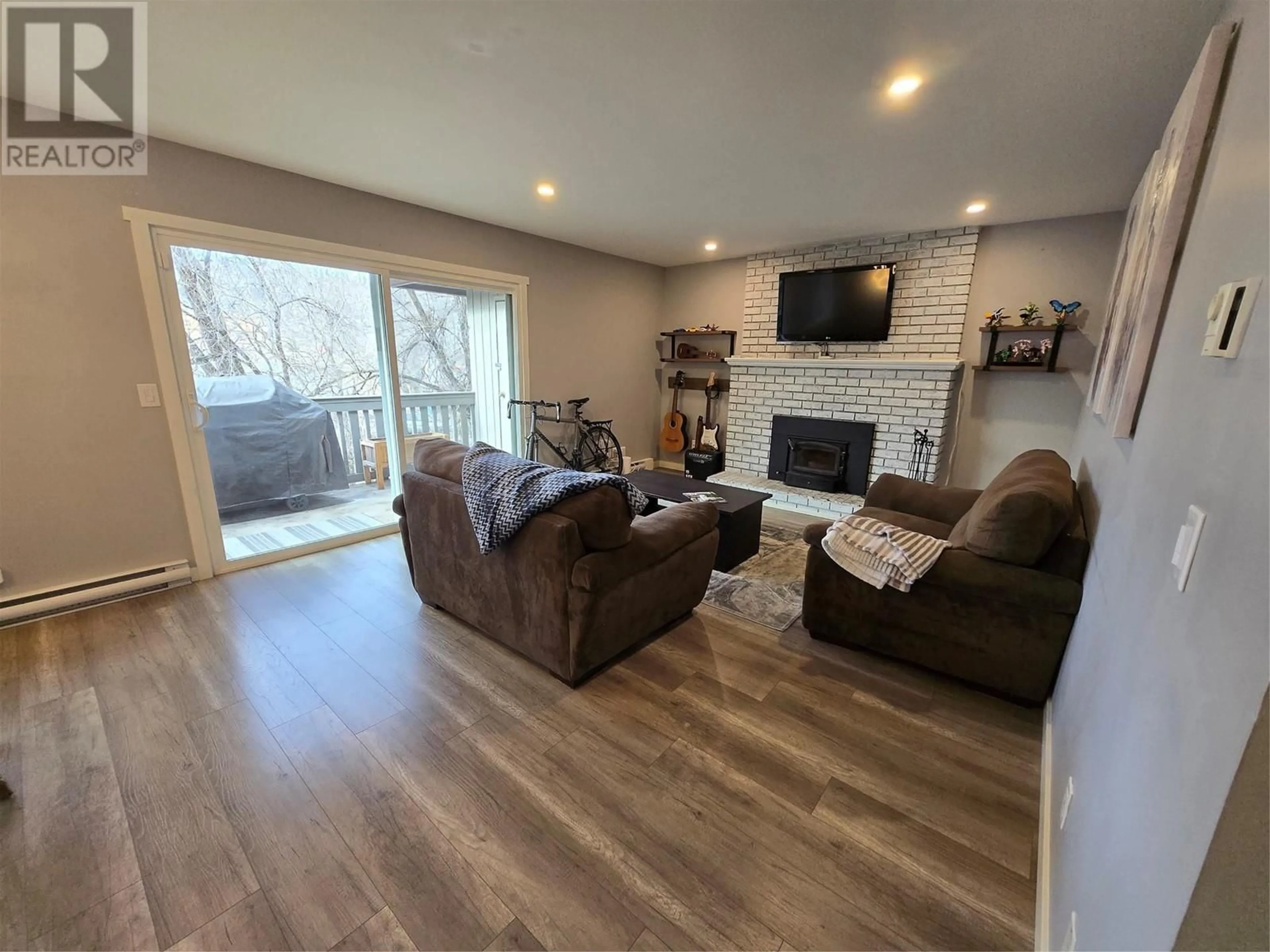 Living room with furniture, wood/laminate floor for 340 Mills Road Unit# 10, Kelowna British Columbia V1X4G8