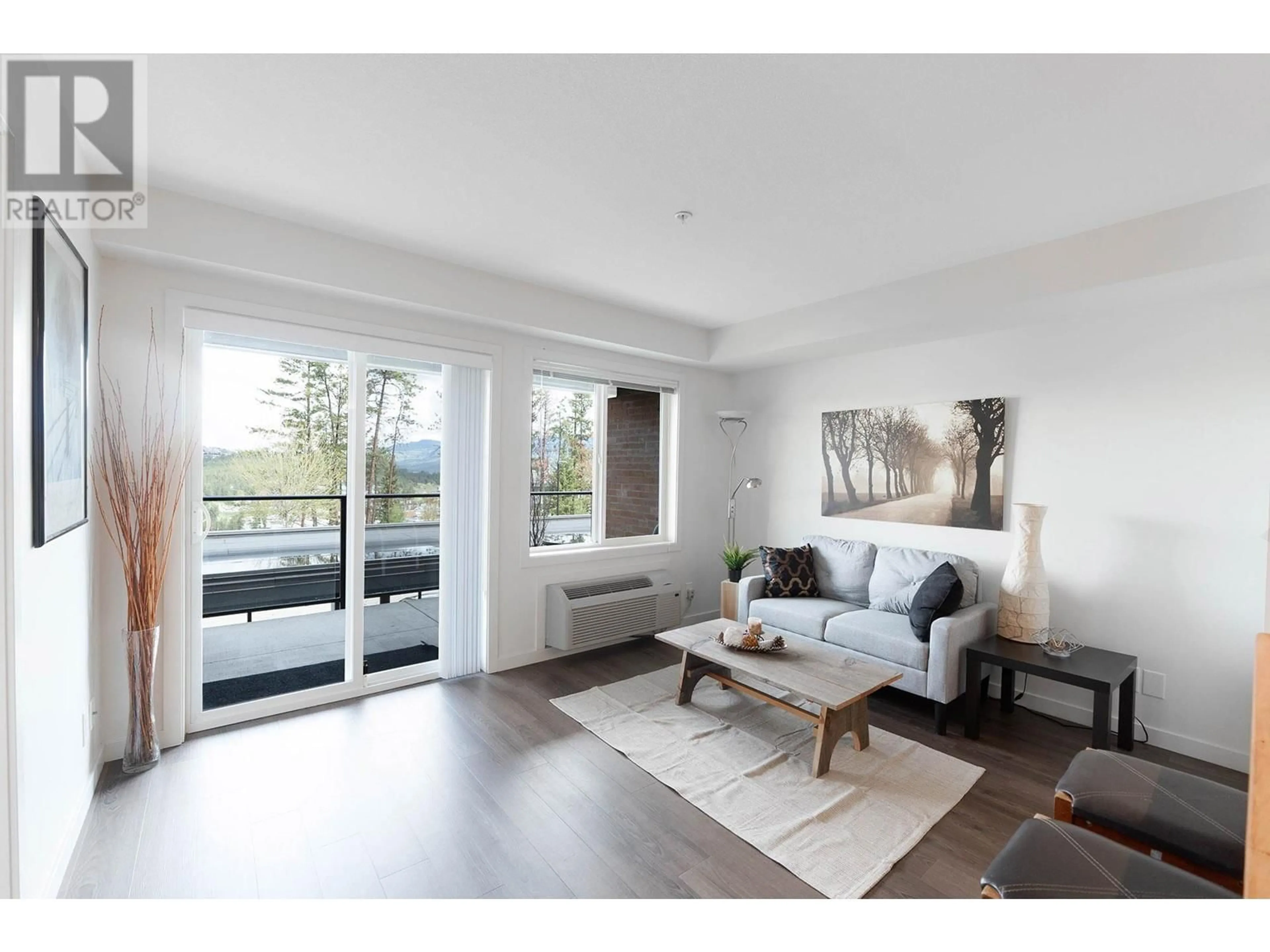 Living room with furniture, wood/laminate floor for 881 Academy Way Unit# 103, Kelowna British Columbia V1V0A2