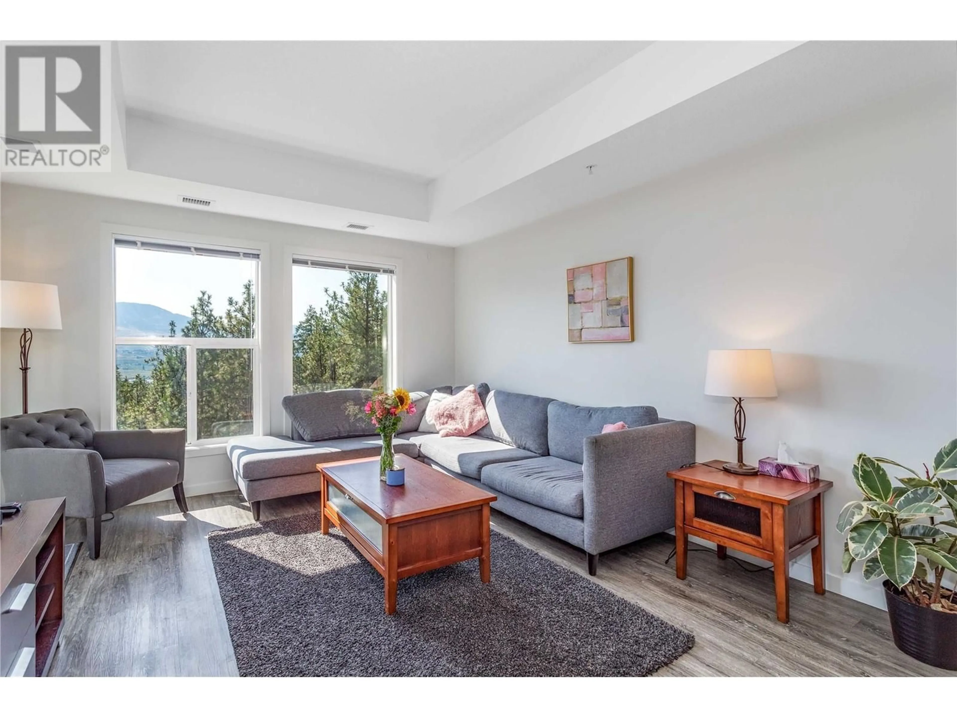 Living room with furniture, wood/laminate floor for 935 Academy Way Unit# 312, Kelowna British Columbia V1V3C9