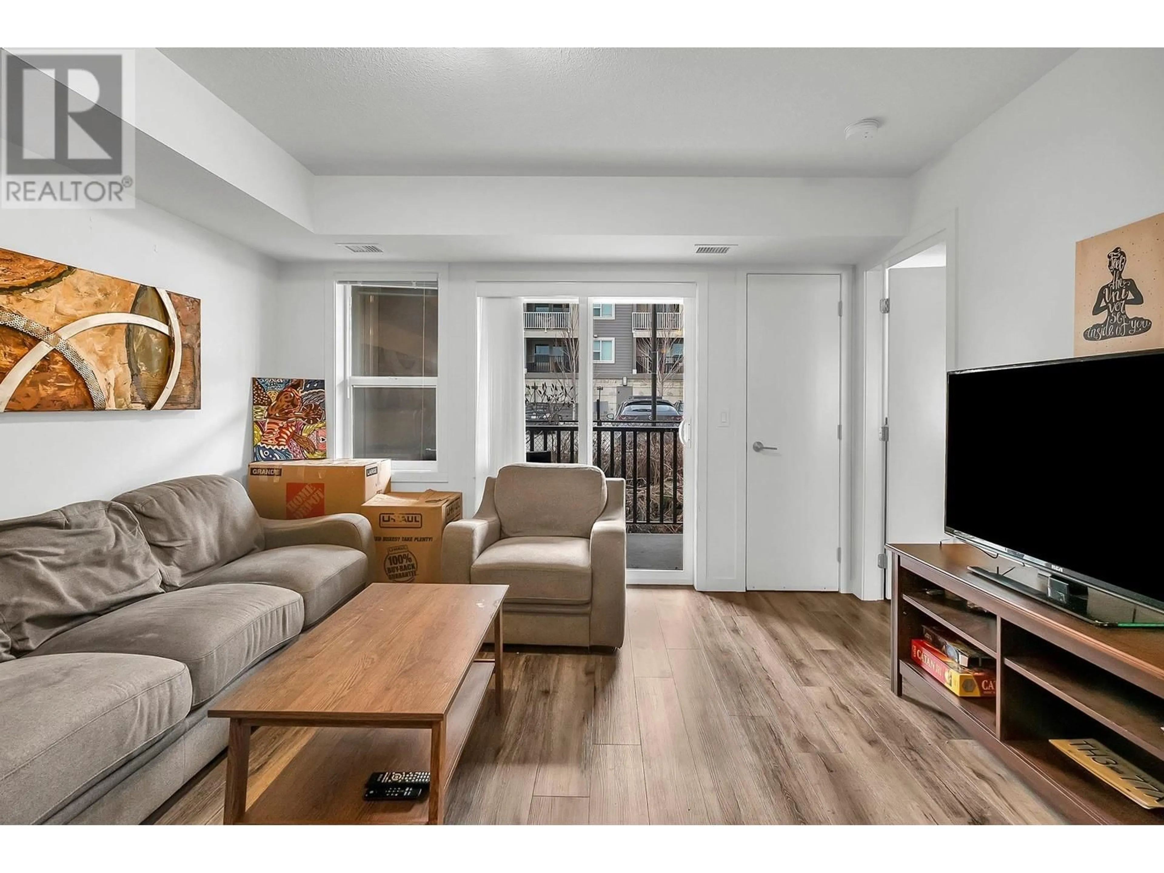 Living room with furniture, wood/laminate floor for 655 Academy Way Unit# 211, Kelowna British Columbia V1V0A2