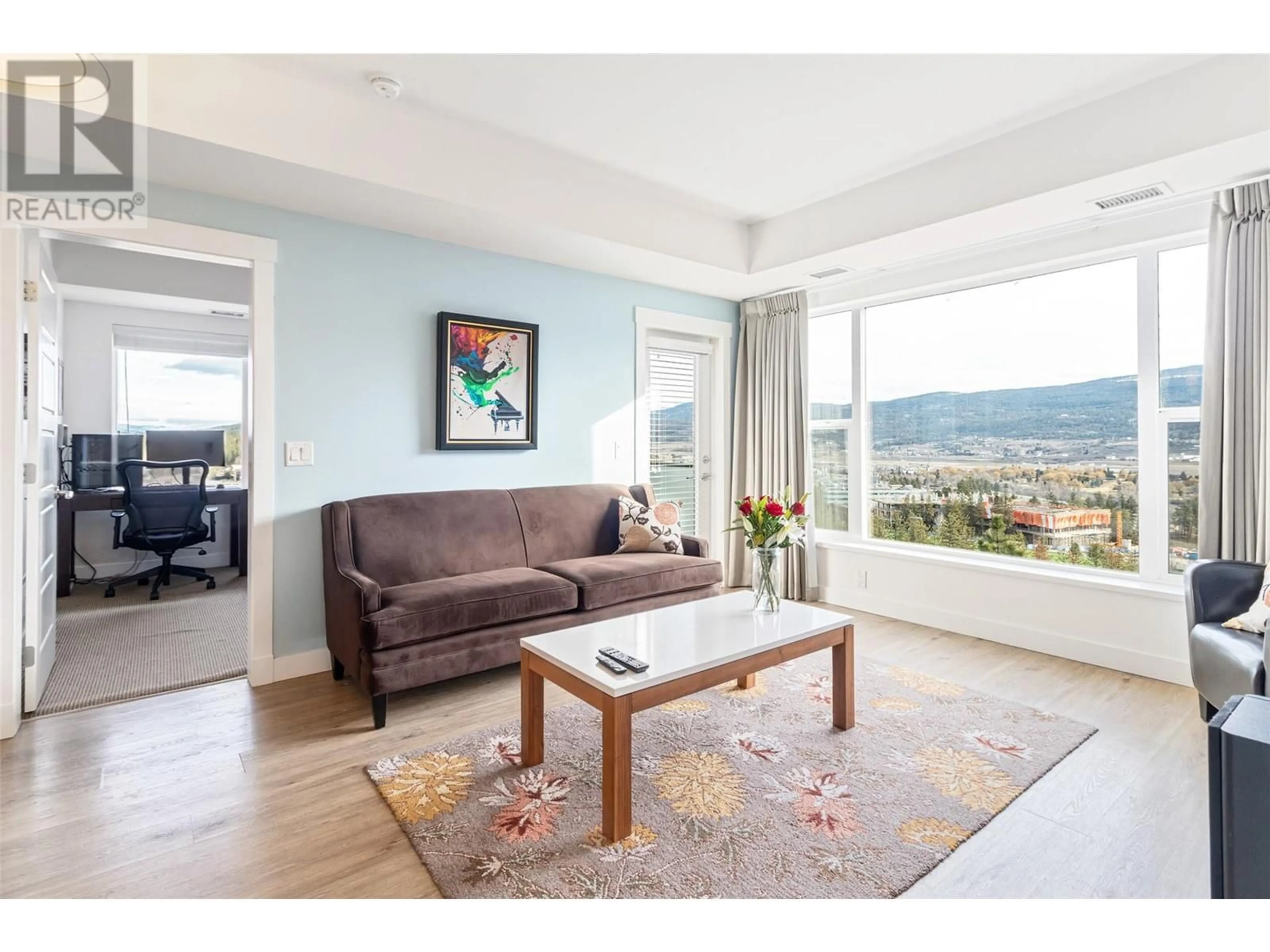 Living room with furniture, wood/laminate floor for 985 Academy Way Unit# 302, Kelowna British Columbia V1V3C8