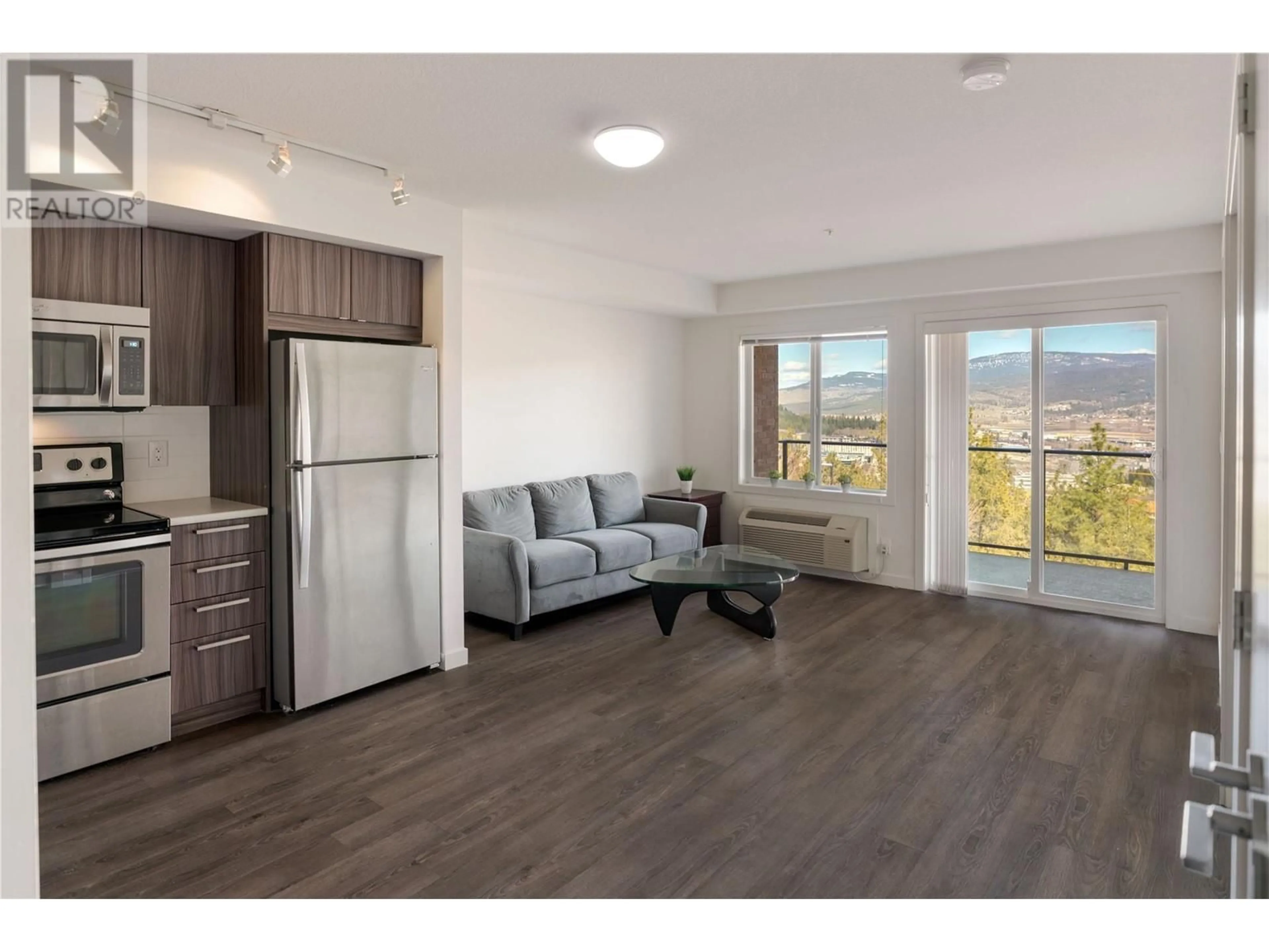 Living room with furniture, wood/laminate floor for 883 Academy Way Unit# 203, Kelowna British Columbia V1V0A3