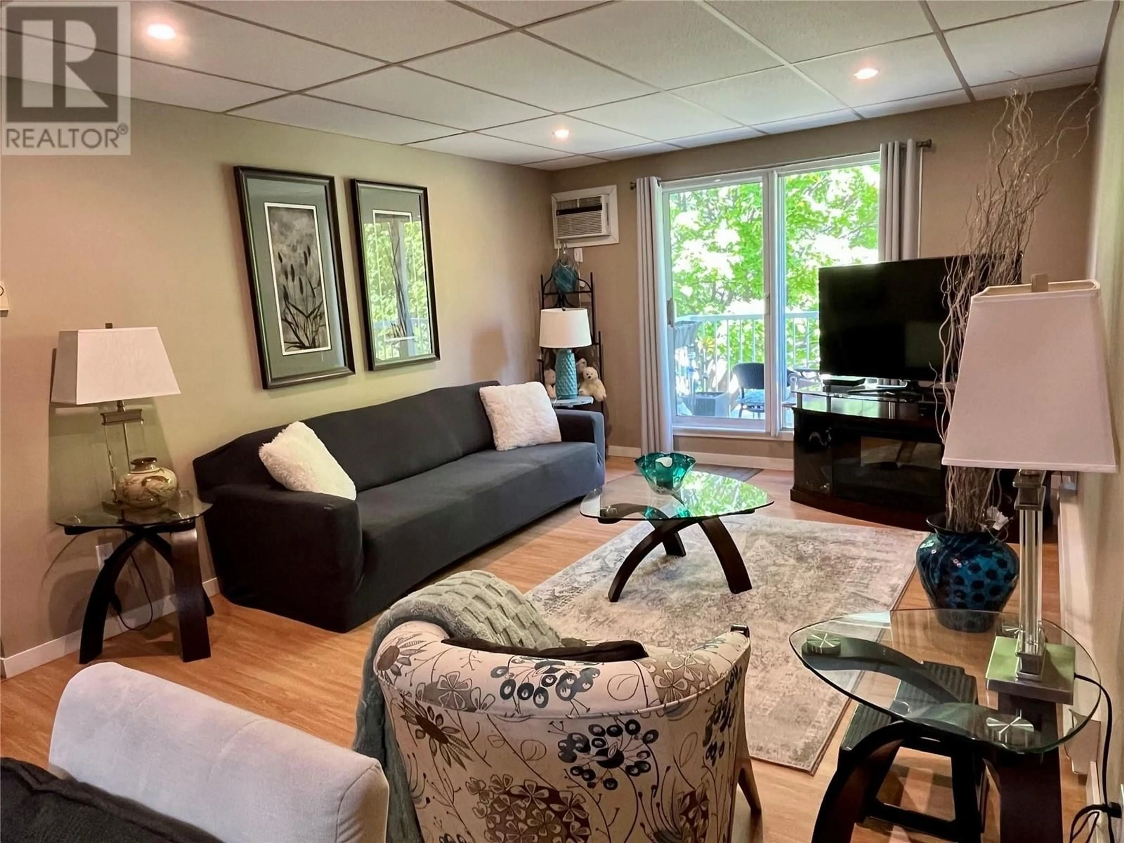 Living room with furniture, wood/laminate floor for 202 - 1410 PENTICTON AVENUE, Penticton British Columbia V2A2N5