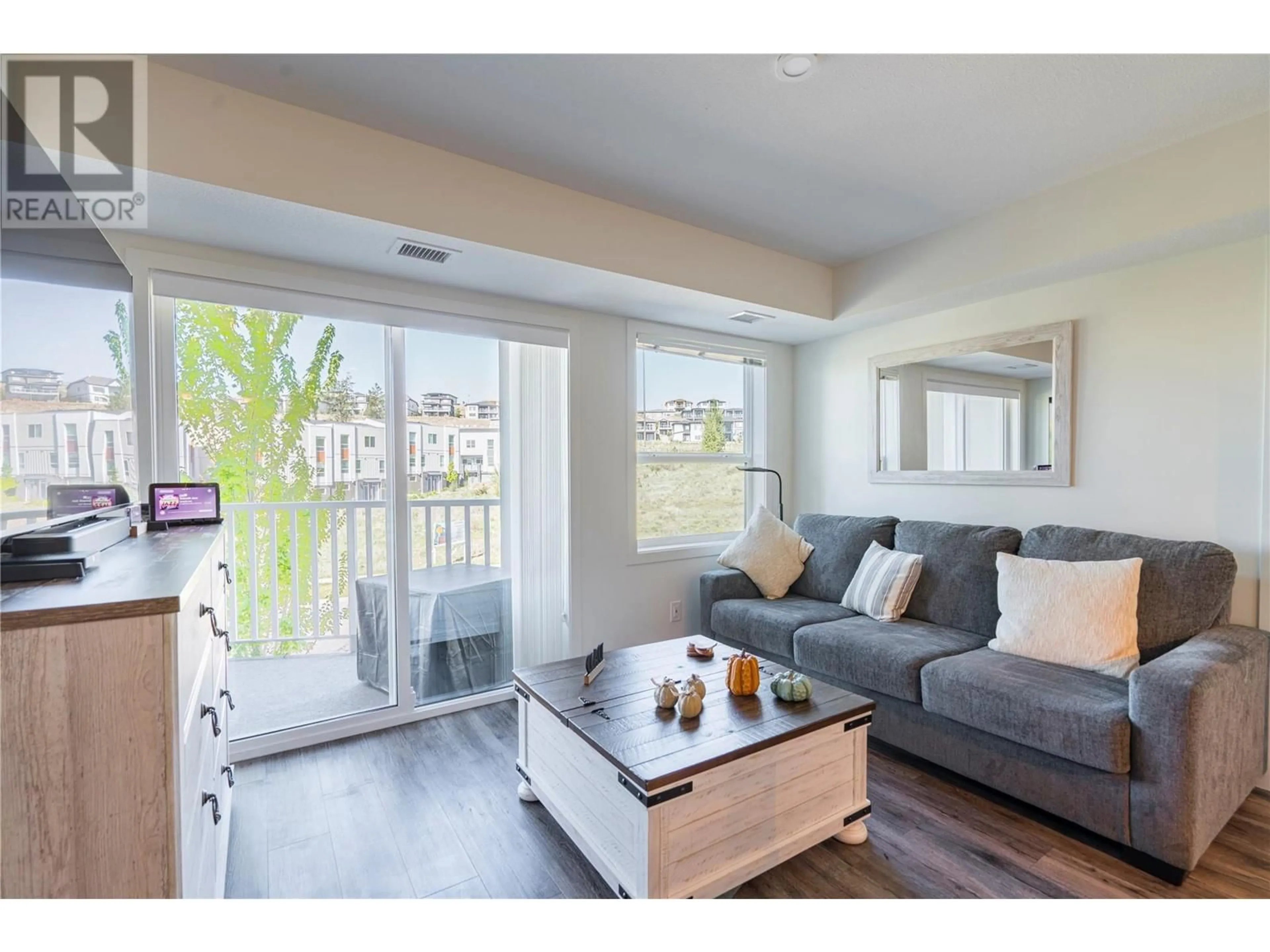 Living room with furniture, wood/laminate floor for 210 - 625 ACADEMY WAY, Kelowna British Columbia V1V0E3