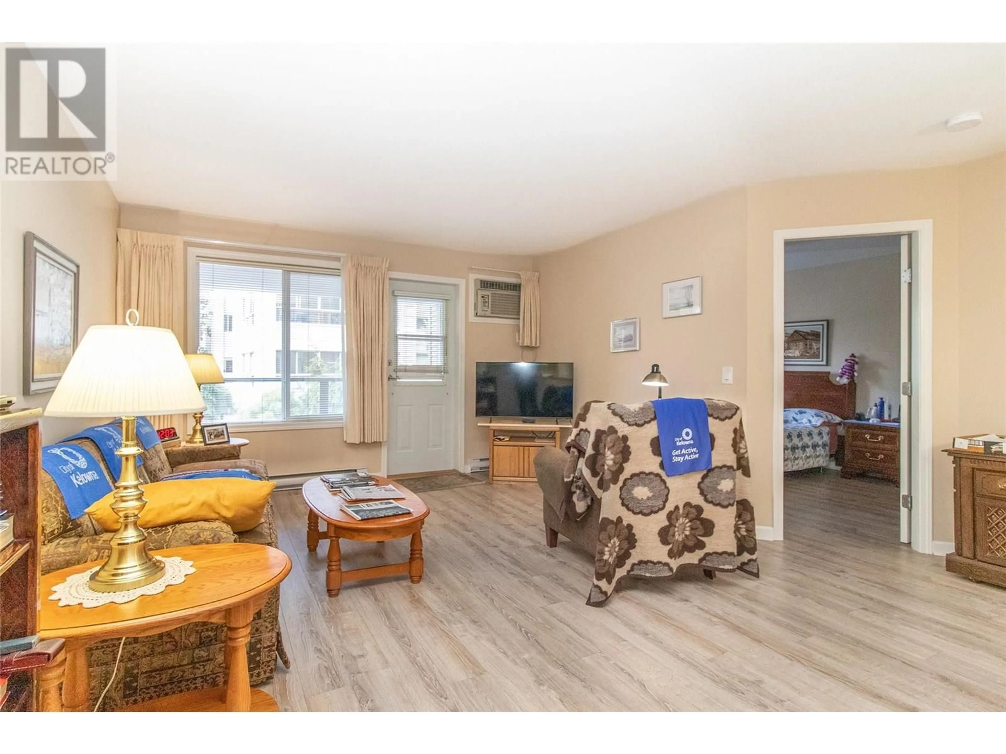 Living room with furniture, wood/laminate floor for 107 - 980 GLENWOOD AVENUE, Kelowna British Columbia V1Y9P2