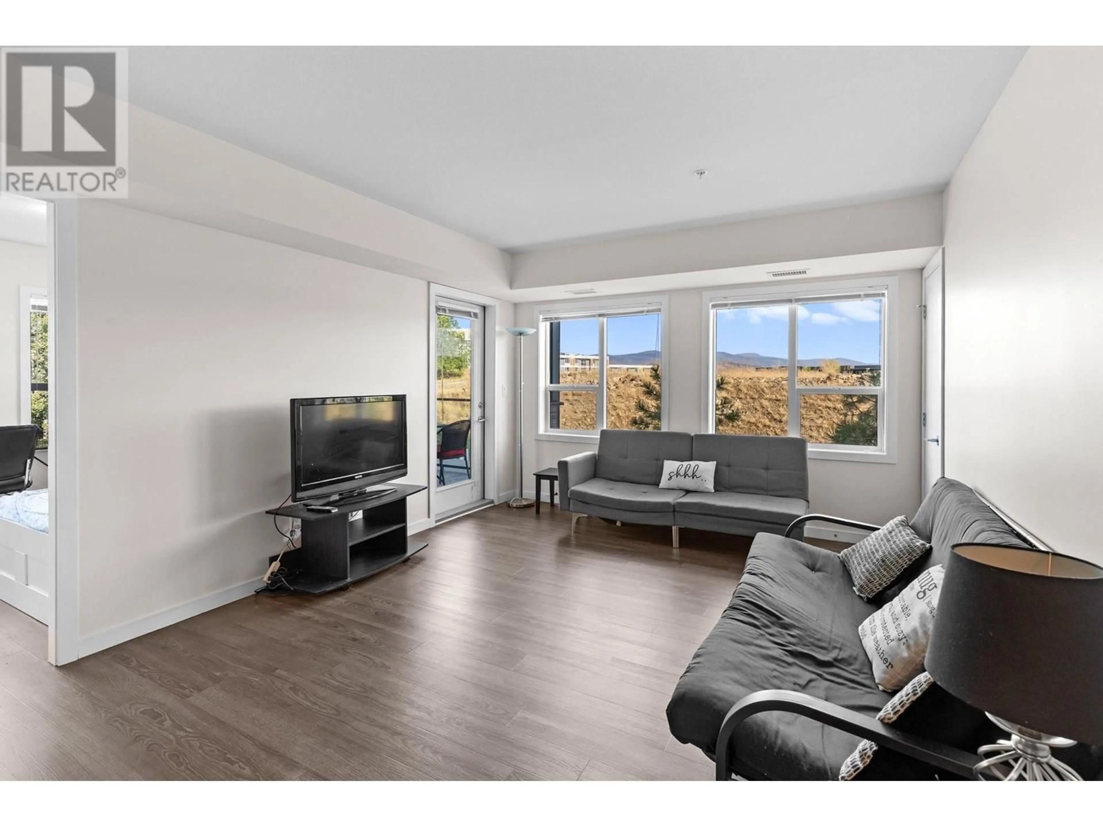 Living room with furniture, wood/laminate floor for 107 - 775 ACADEMY WAY, Kelowna British Columbia V4C2C6