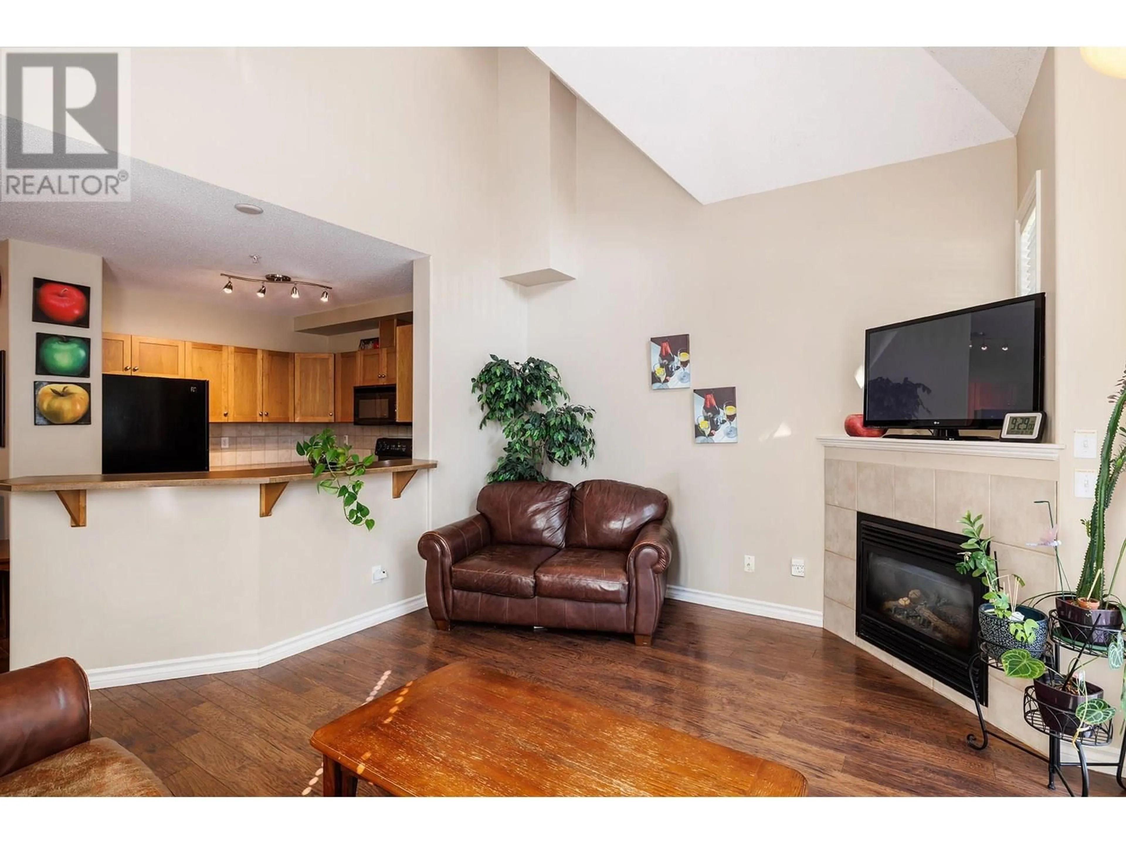 Living room with furniture, wood/laminate floor for 102 - 1128 SUNSET DRIVE, Kelowna British Columbia V1Y9W1