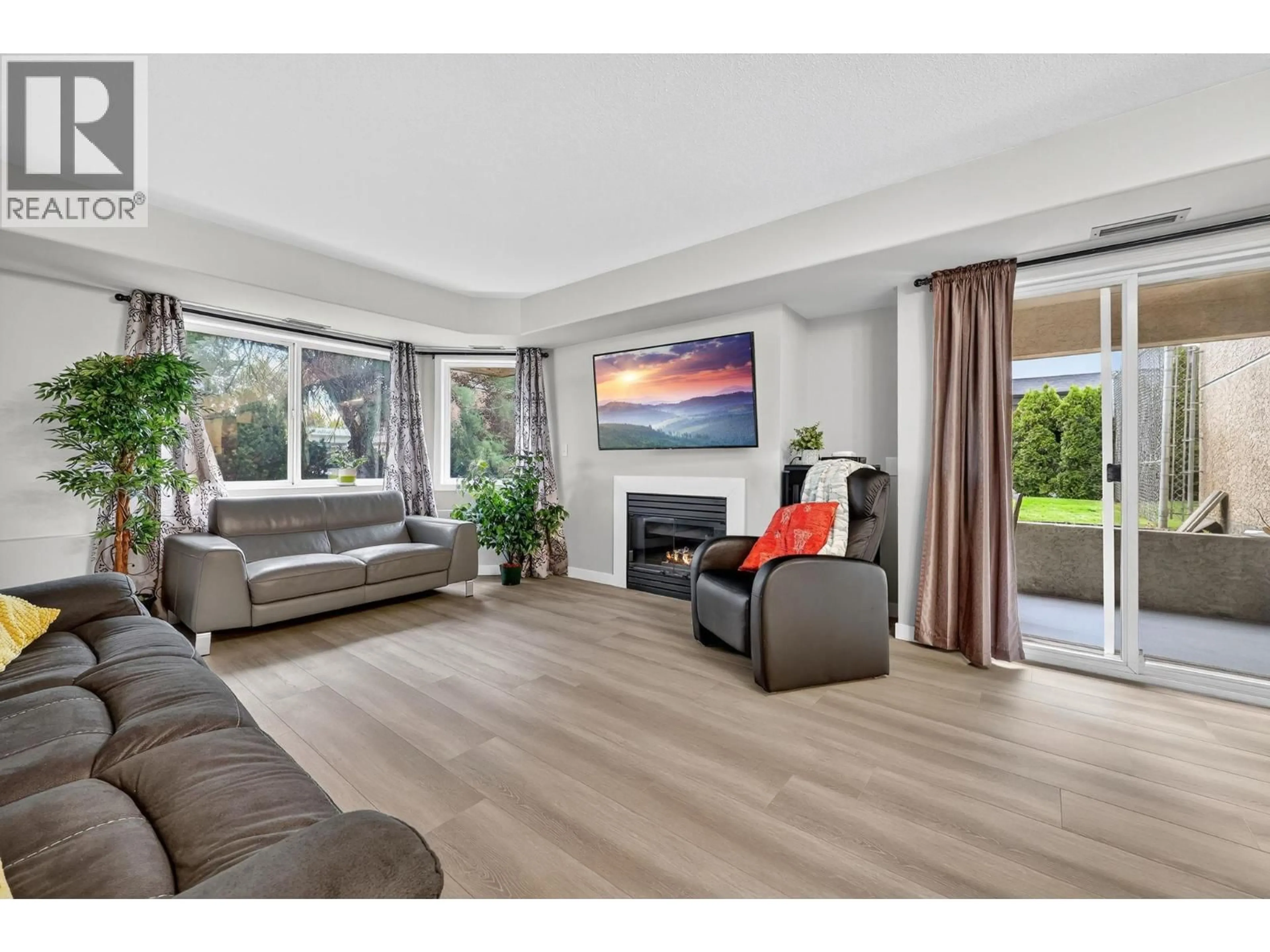 Living room with furniture, wood/laminate floor for 105 - 3115 DE MONTREUIL COURT, Kelowna British Columbia V1W3W1