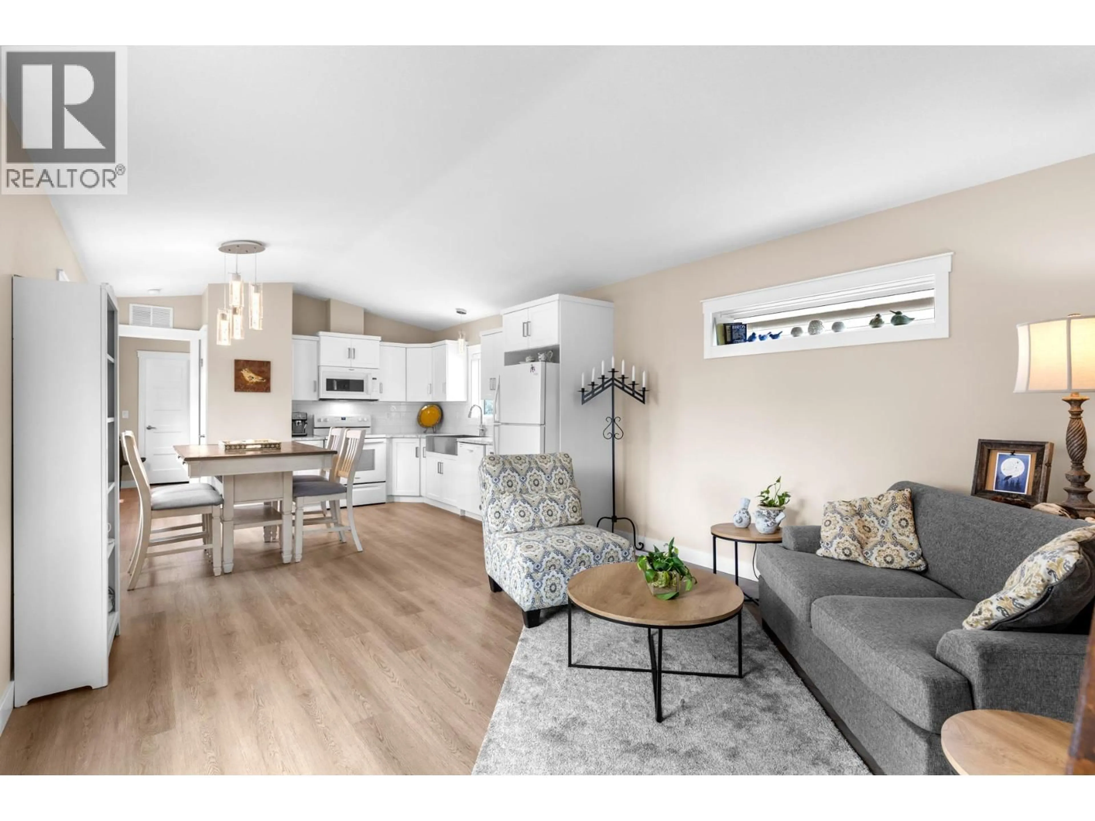 Living room with furniture, wood/laminate floor for 101 - 4075 MCCLAIN ROAD, Kelowna British Columbia V1W4R4