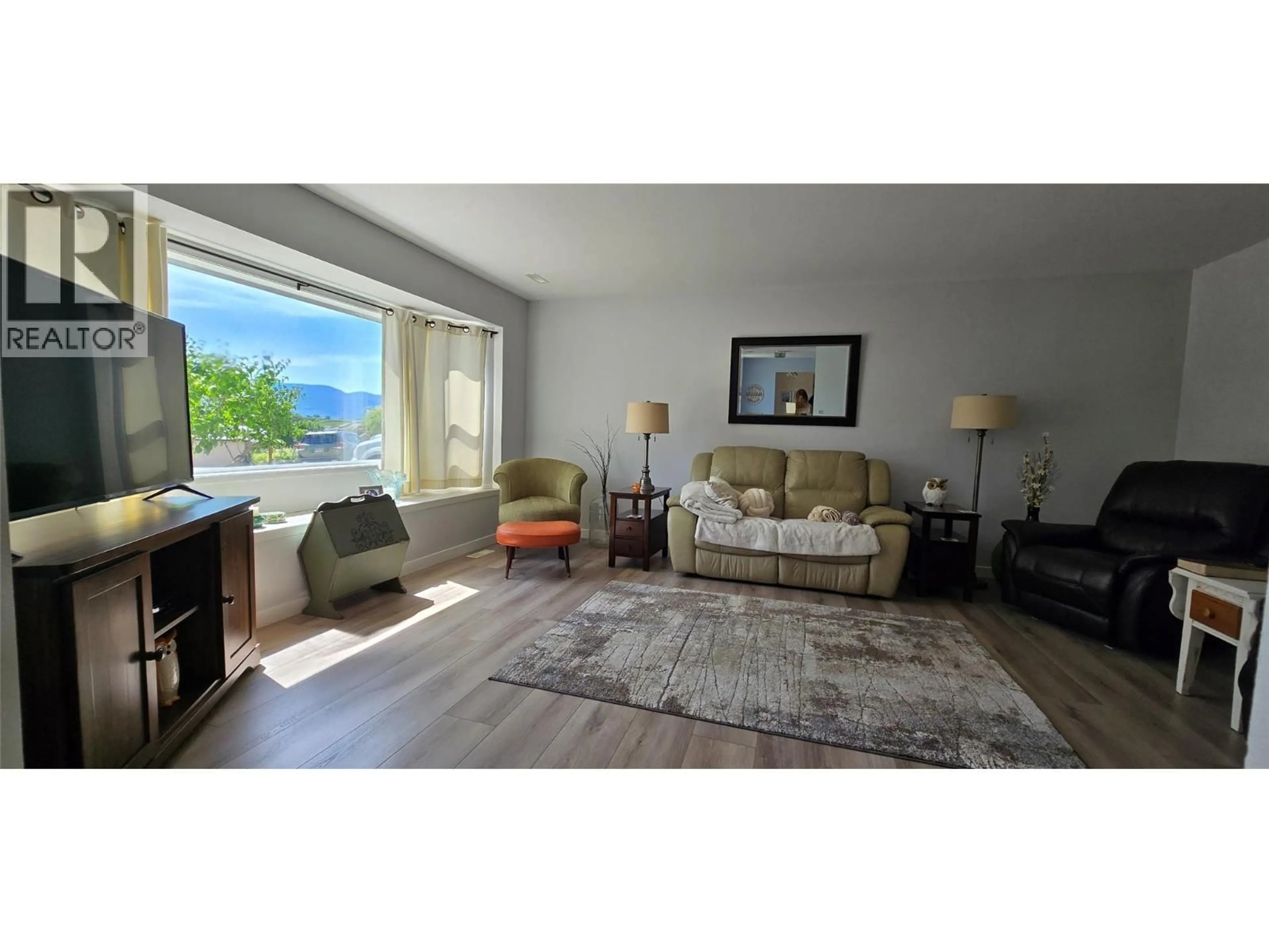 Living room with furniture, wood/laminate floor for 9517 62 AVENUE, Osoyoos British Columbia V0H1V1