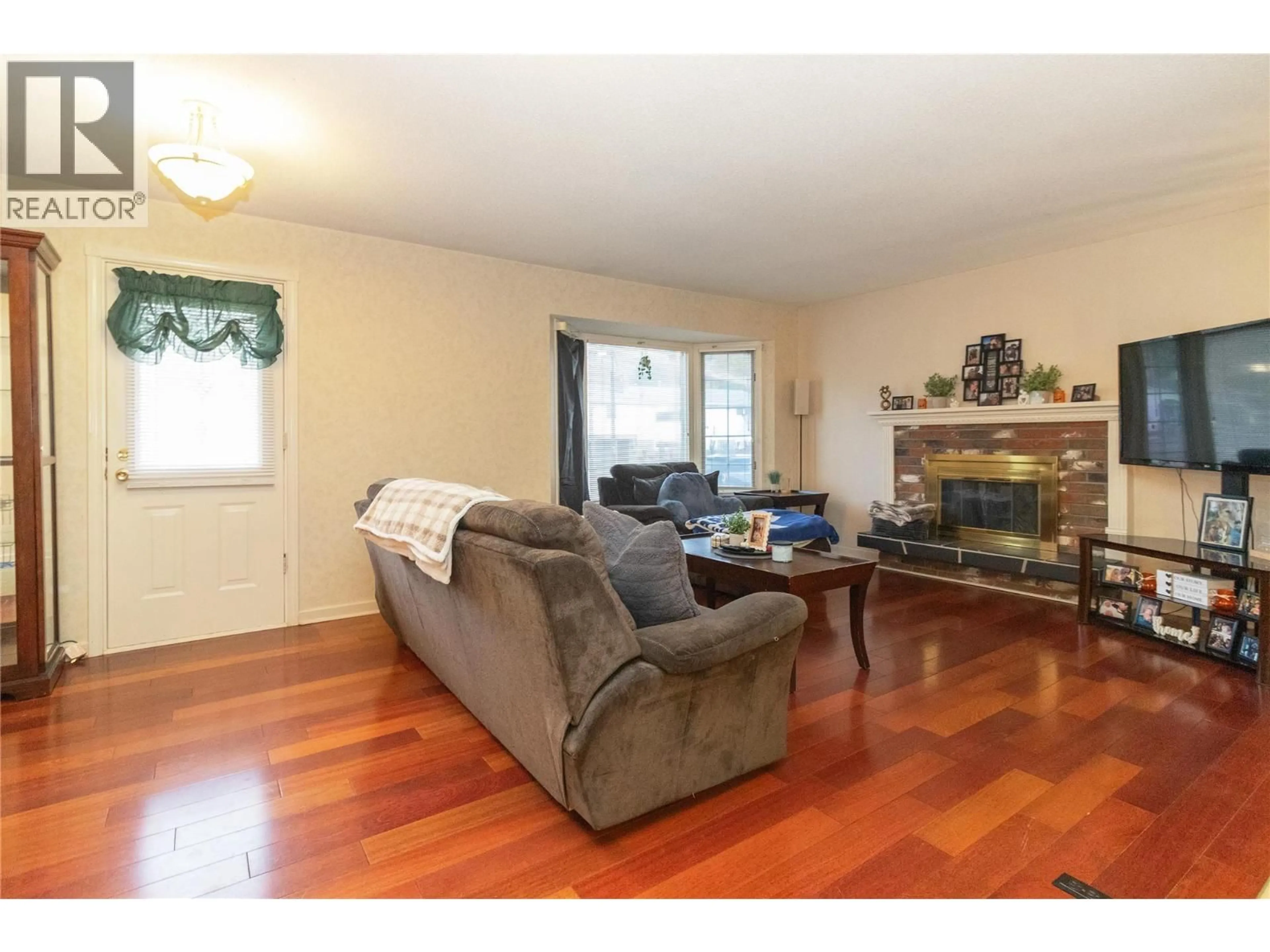 Living room with furniture, wood/laminate floor for 1040 CACTUS ROAD, Kelowna British Columbia V1X3N7