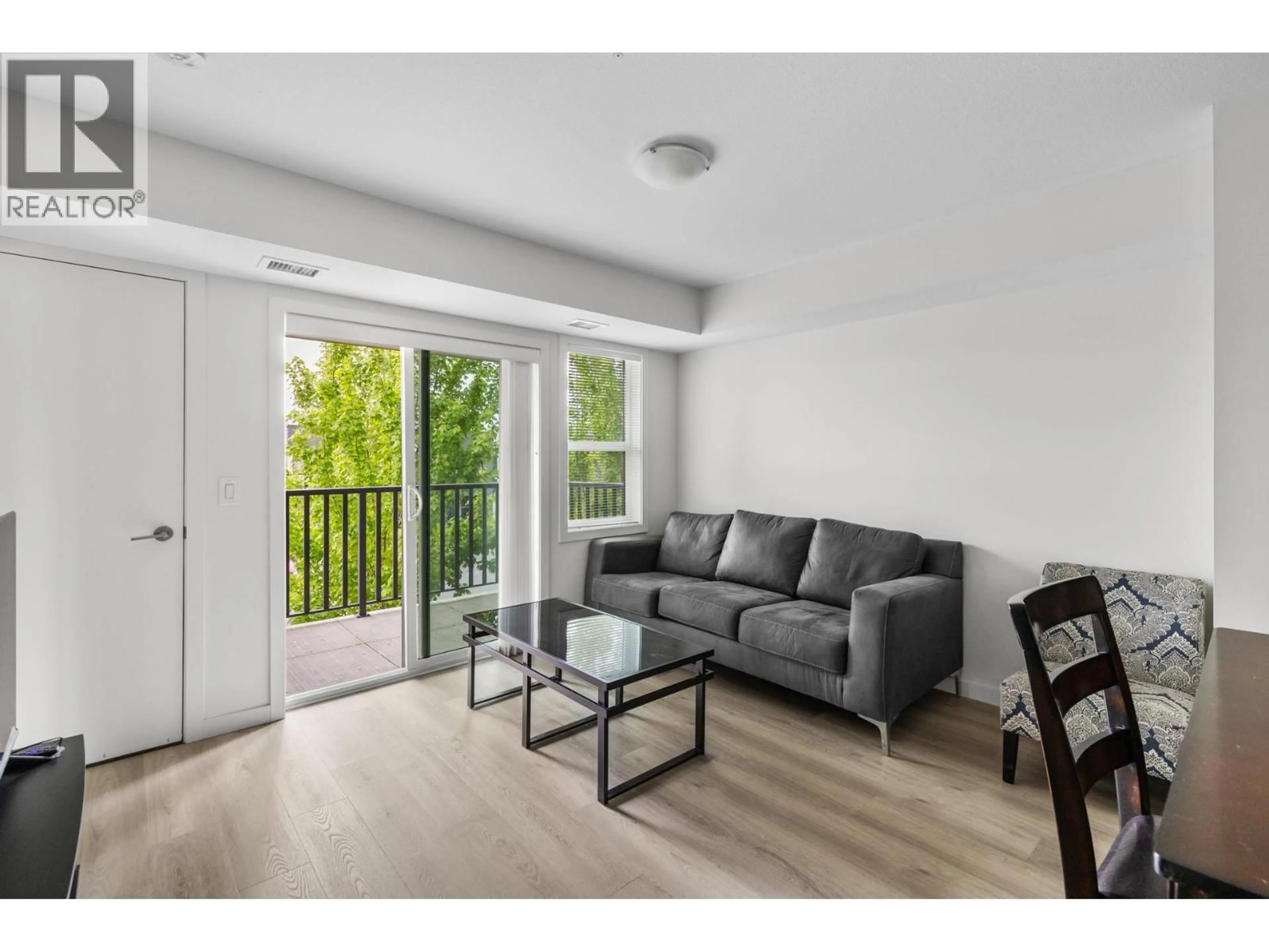 Living room with furniture, wood/laminate floor for 105 - 695 ACADEMY WAY, Kelowna British Columbia V1V0C7