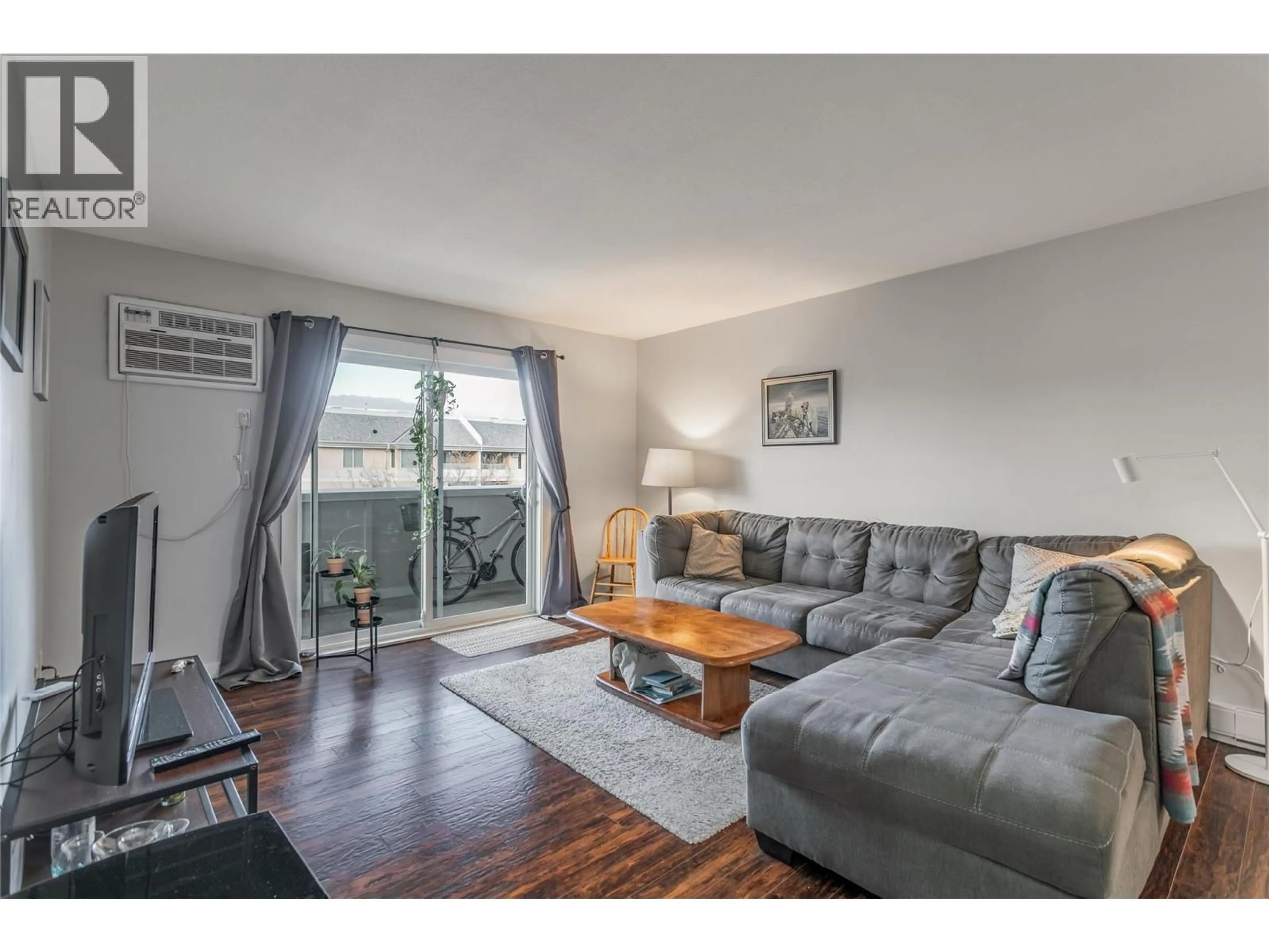 Living room with furniture, wood/laminate floor for 411 - 3160 DE MONTREUIL COURT, Kelowna British Columbia V1W3W3