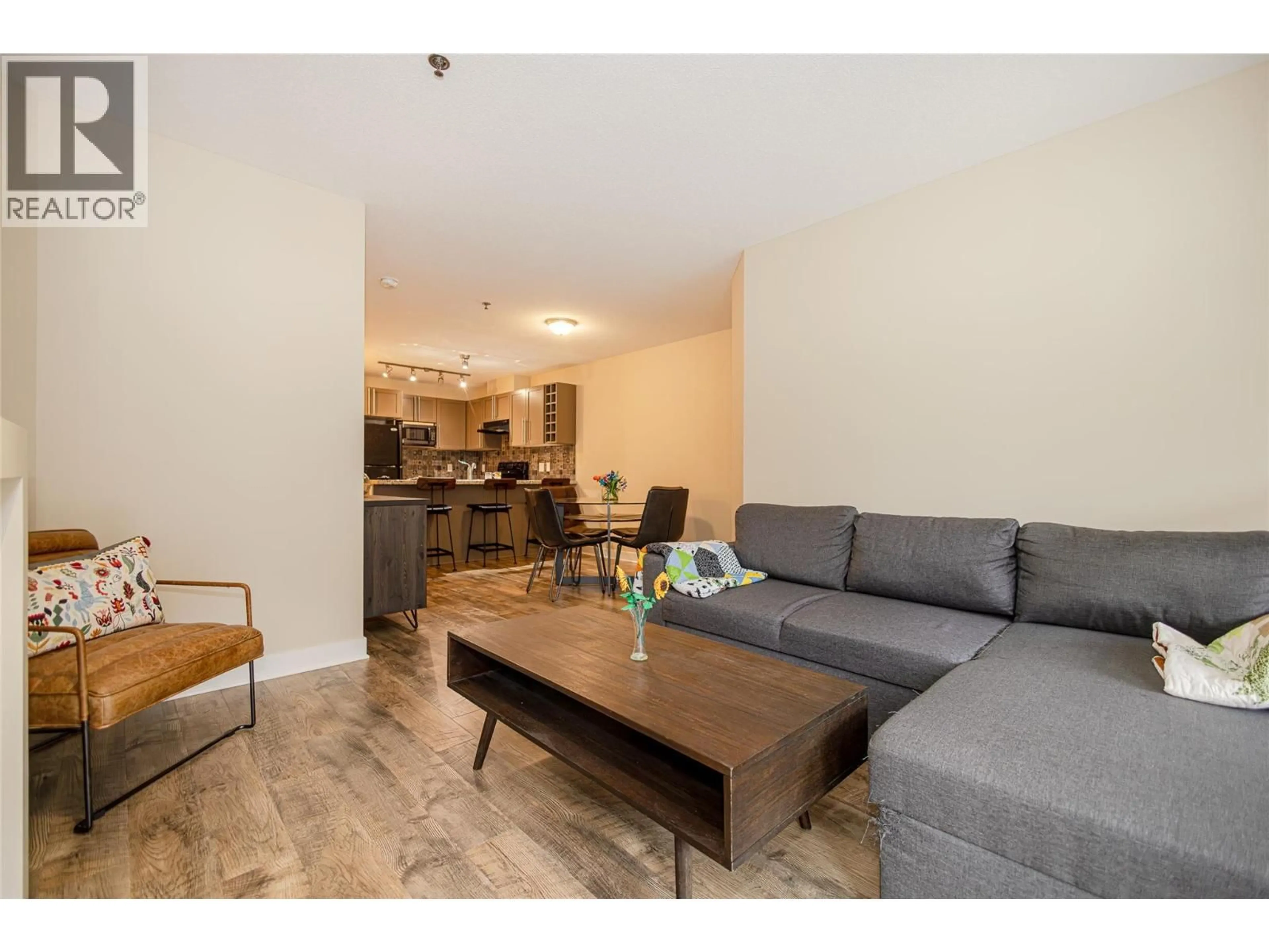 Living room with furniture, wood/laminate floor for 203 - 1093 SUNSET DRIVE, Kelowna British Columbia V1Y9Z4