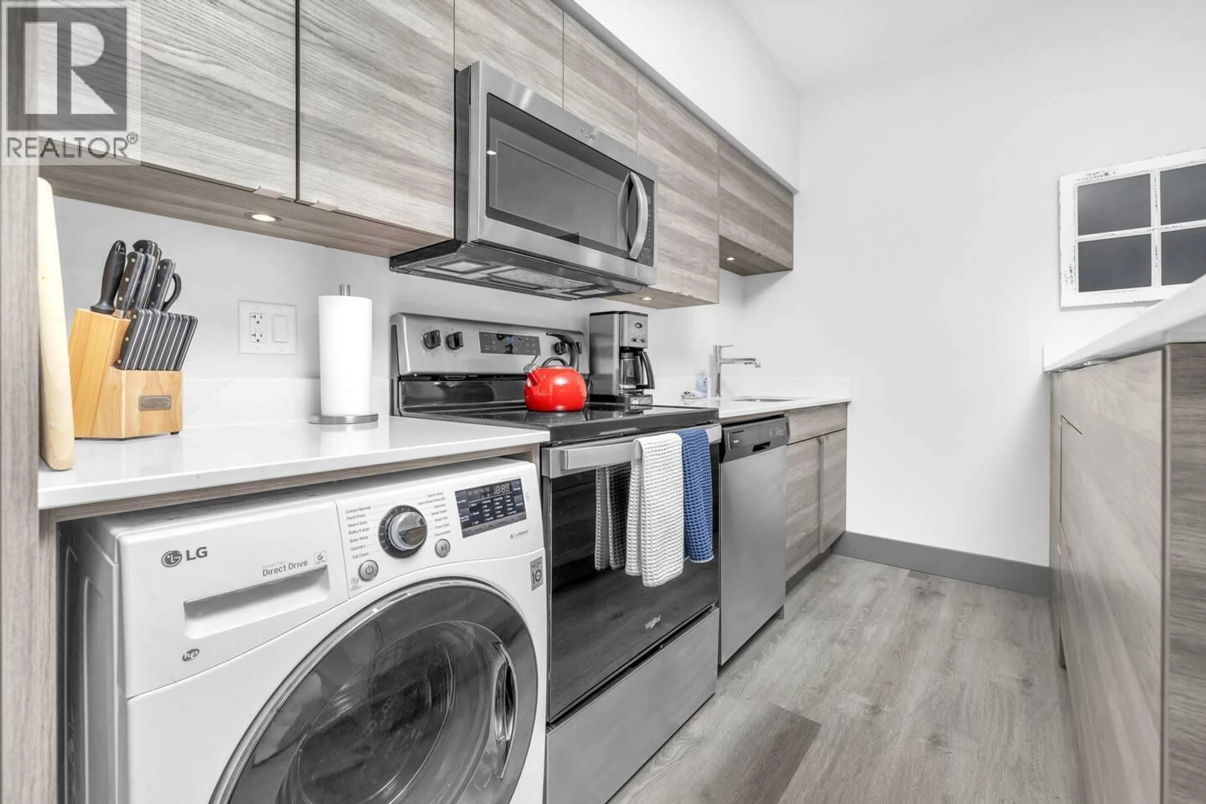 Kitchen with laundary machines, wood/laminate floor for 406 - 2555 LAKESHORE ROAD, Vernon British Columbia V1H1M9