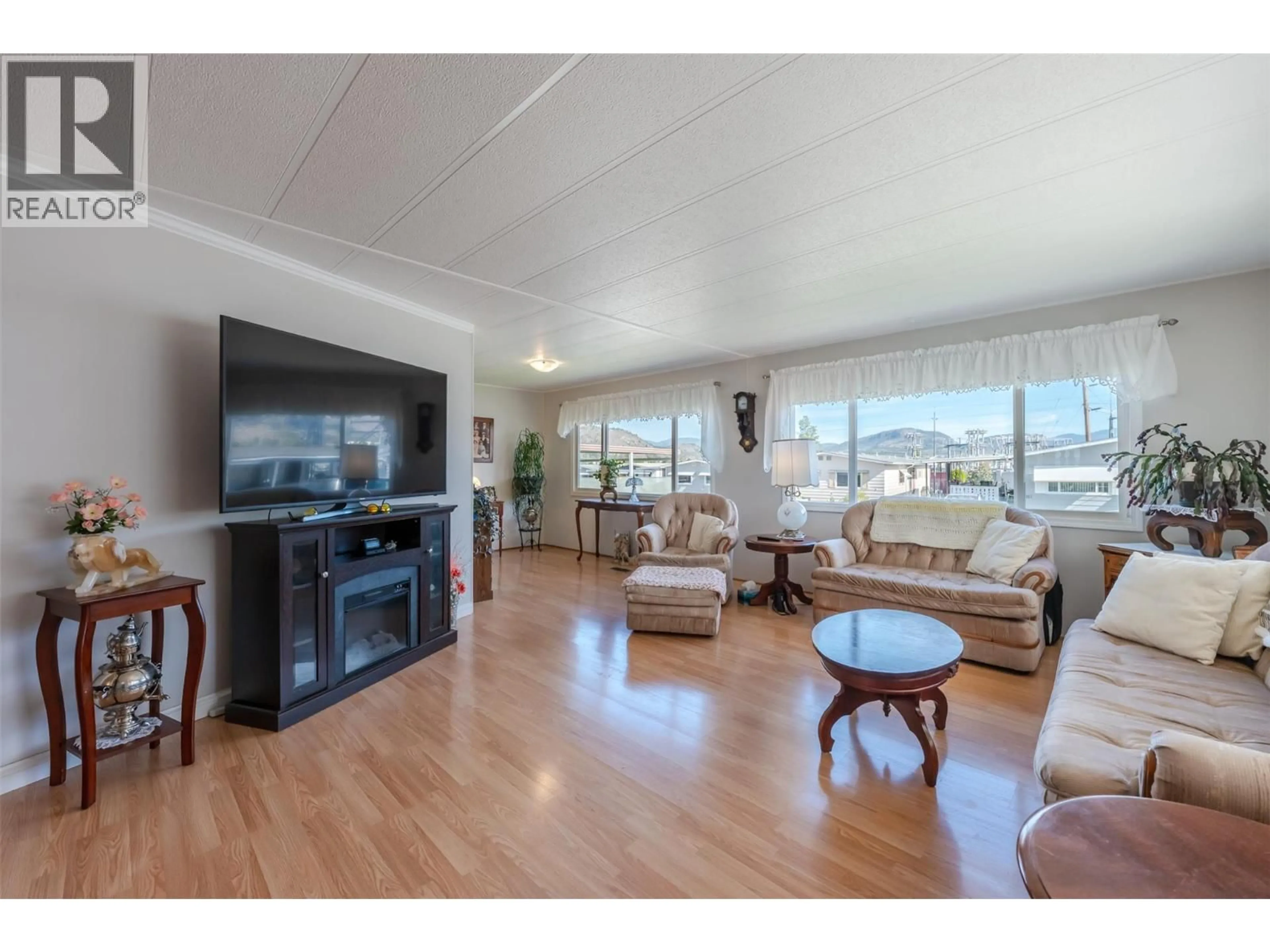 Living room with furniture, wood/laminate floor for 113 - 6601 TUCELNUIT DRIVE, Oliver British Columbia V0H1T3