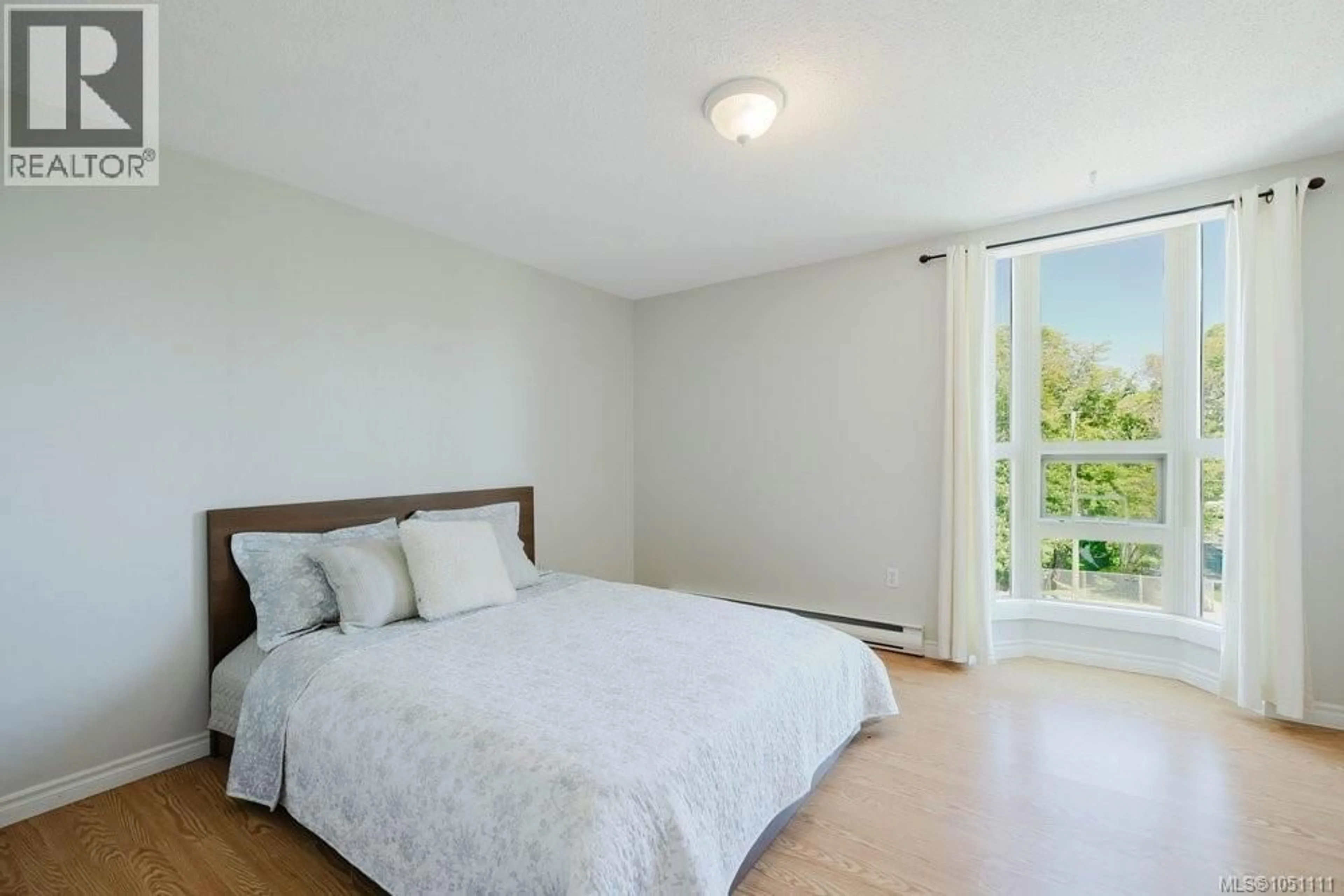 Bedroom with bed, wood/laminate floor for 306 - 1545 PANDORA AVENUE, Victoria British Columbia V8R6R1