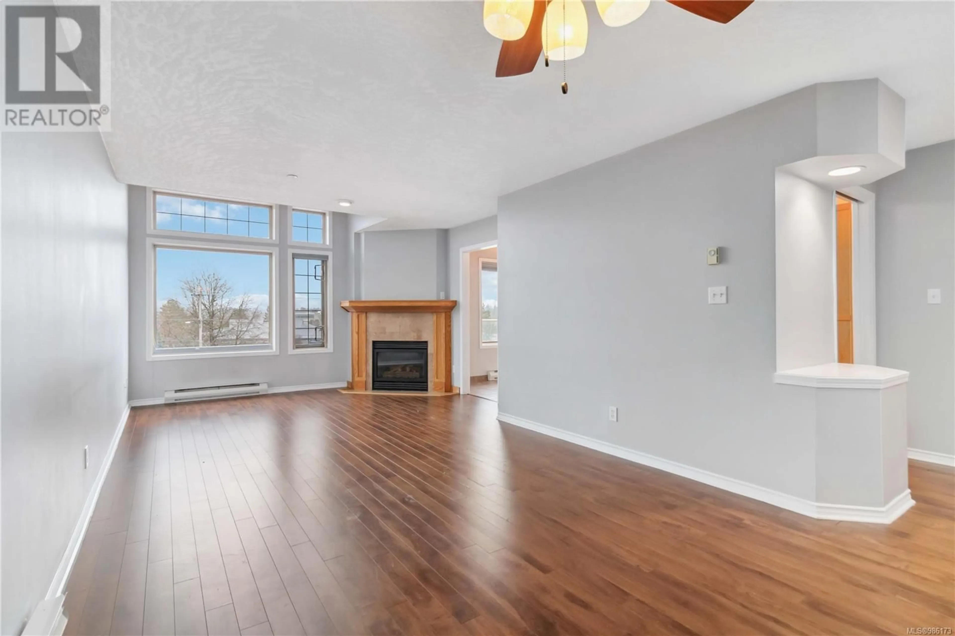 Living room with furniture, wood/laminate floor for 404 3700 Carey Rd, Saanich British Columbia V8Z4C2