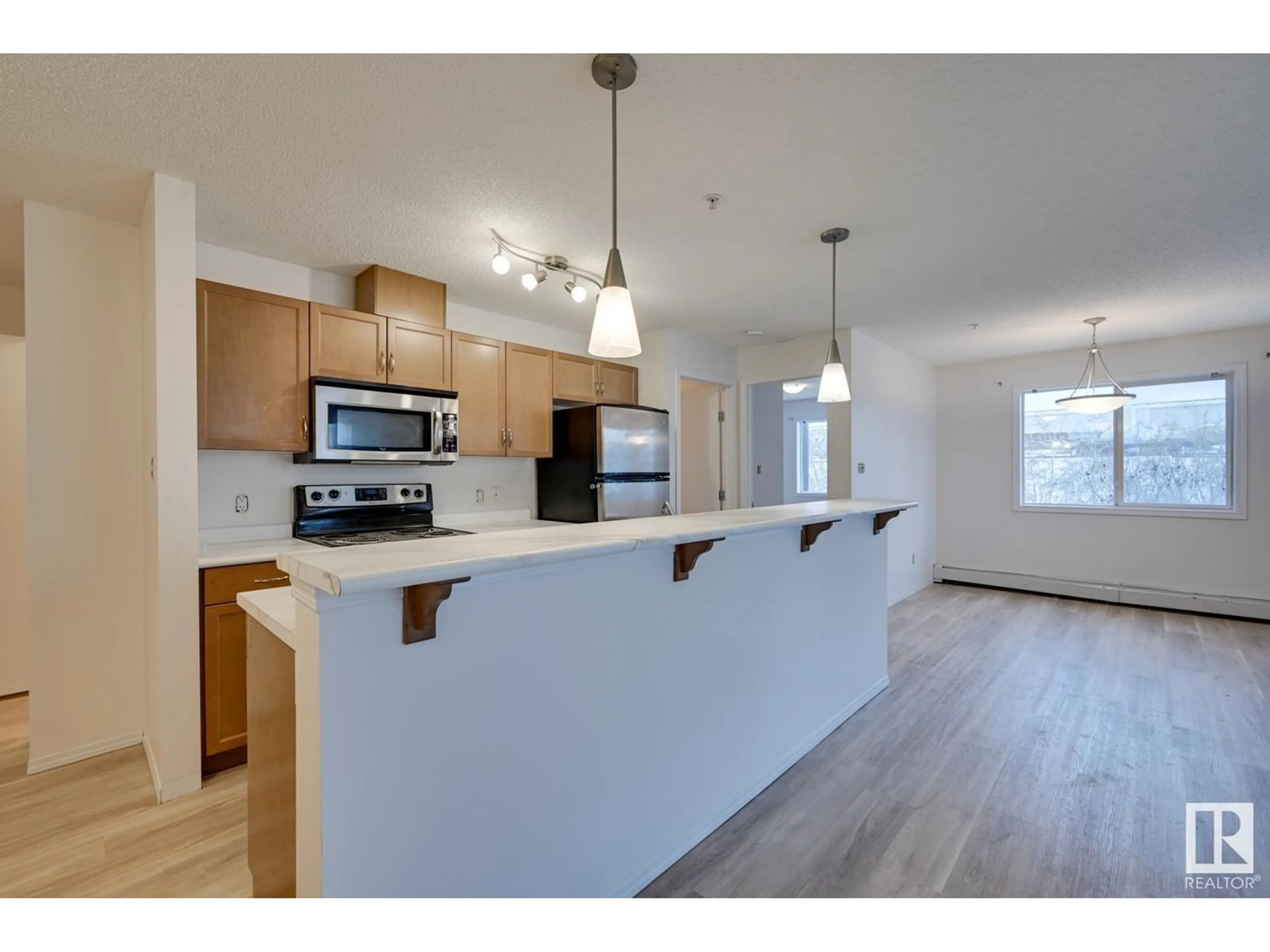 Open concept kitchen, wood/laminate floor for #218 1180 HYNDMAN RD NW, Edmonton Alberta T5A0P8