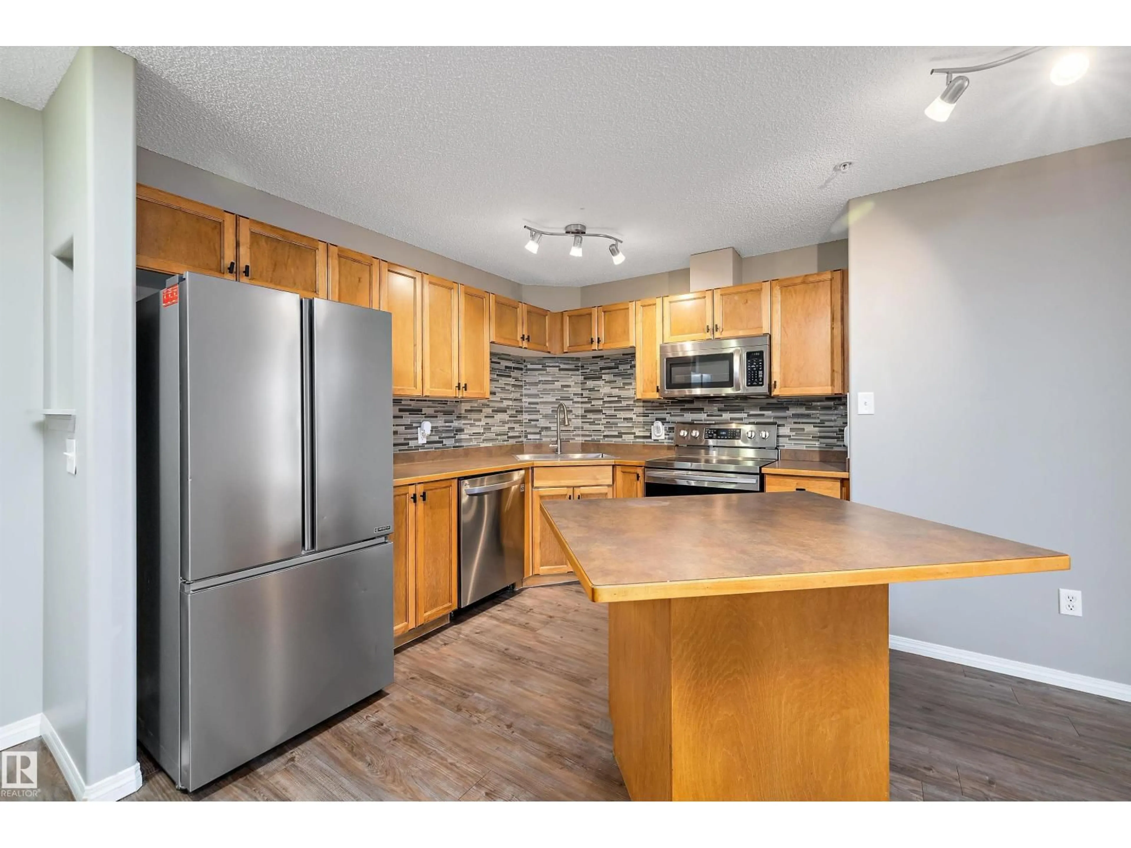 Open concept kitchen, wood/laminate floor for #421 - 5350 199 ST, Edmonton Alberta T6M0A4