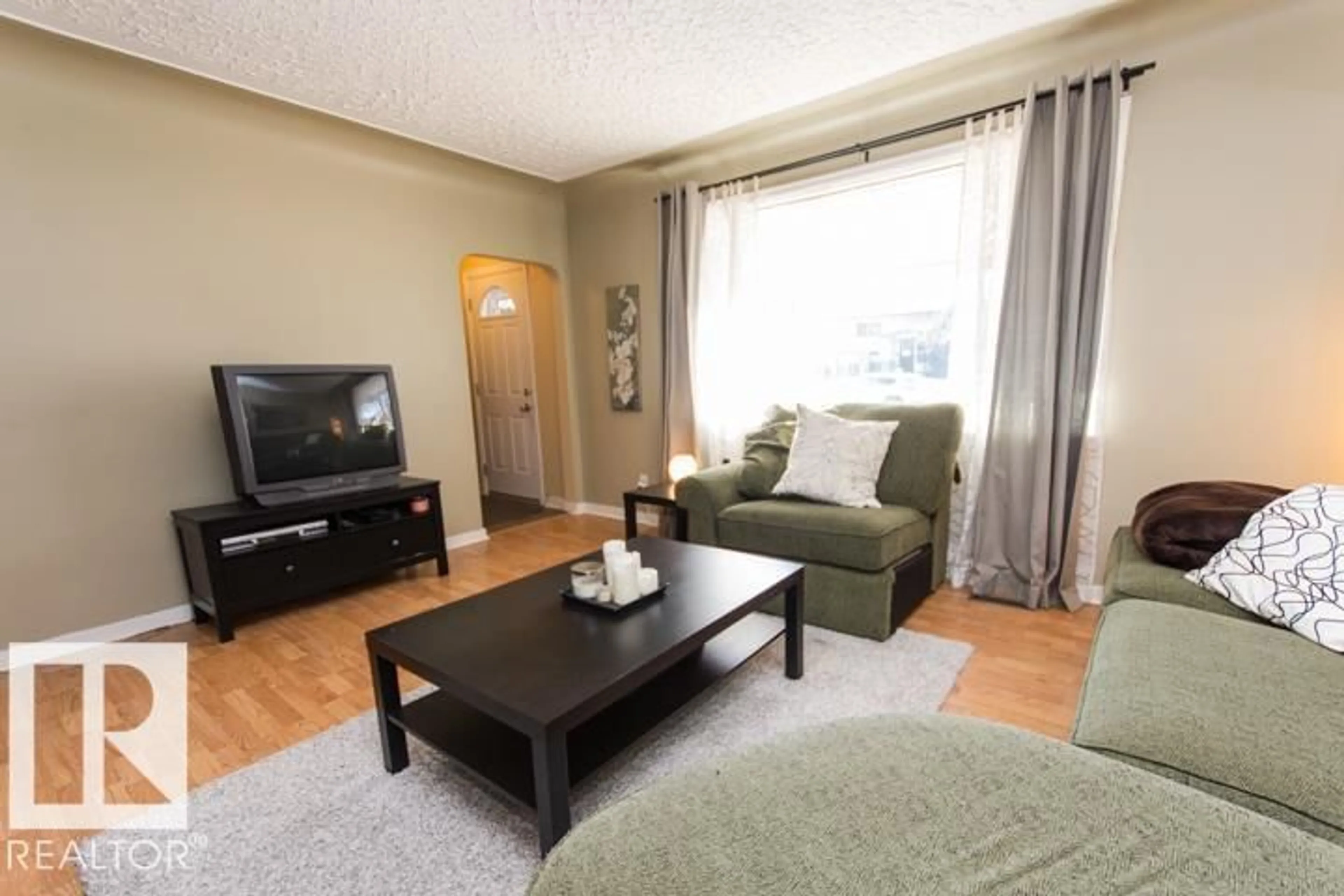 Living room with furniture, wood/laminate floor for 10806 64 AV, Edmonton Alberta T6H1T2