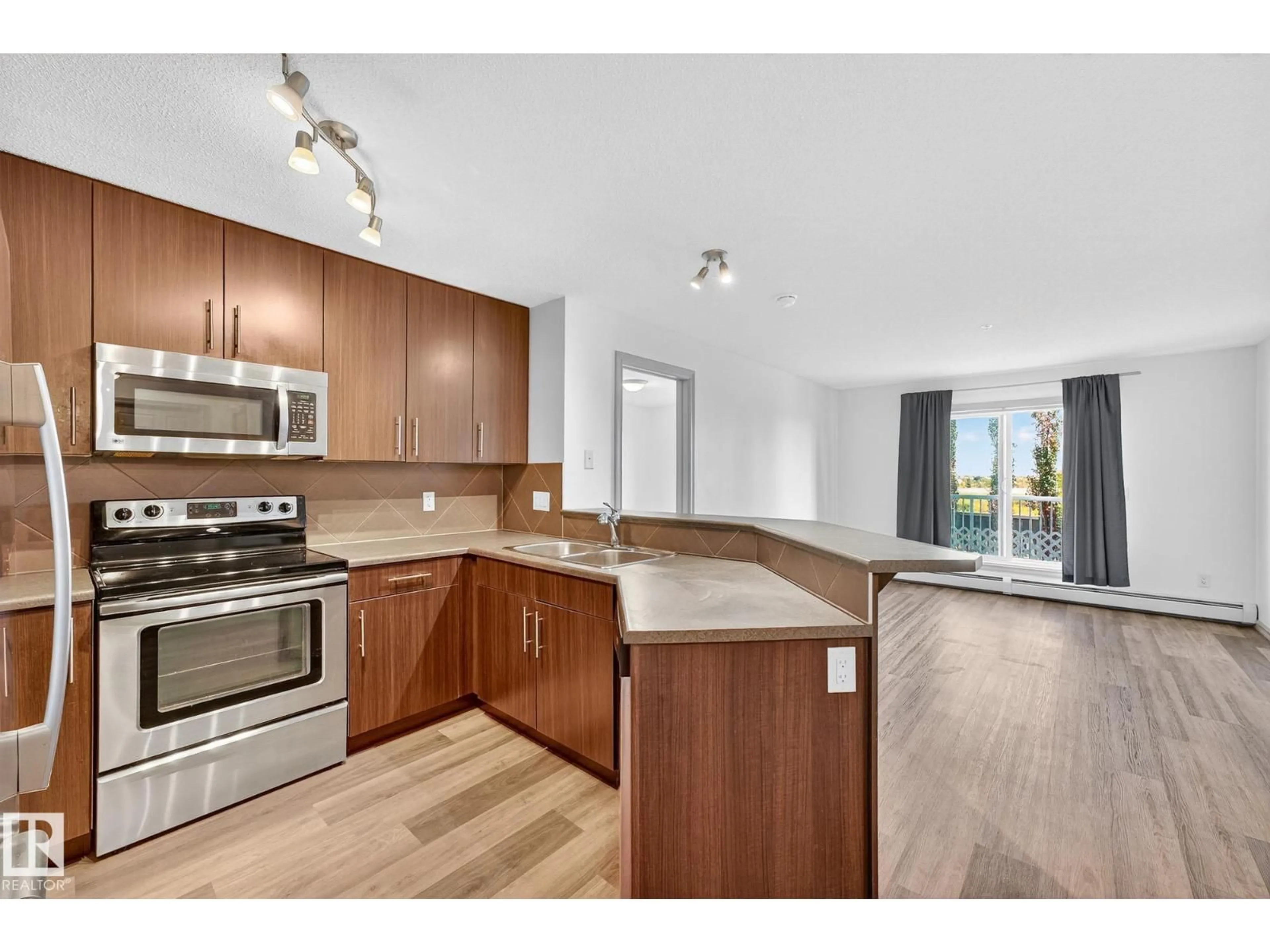 Open concept kitchen, wood/laminate floor for #215 - 2208 44 AV NW, Edmonton Alberta T6T0G6