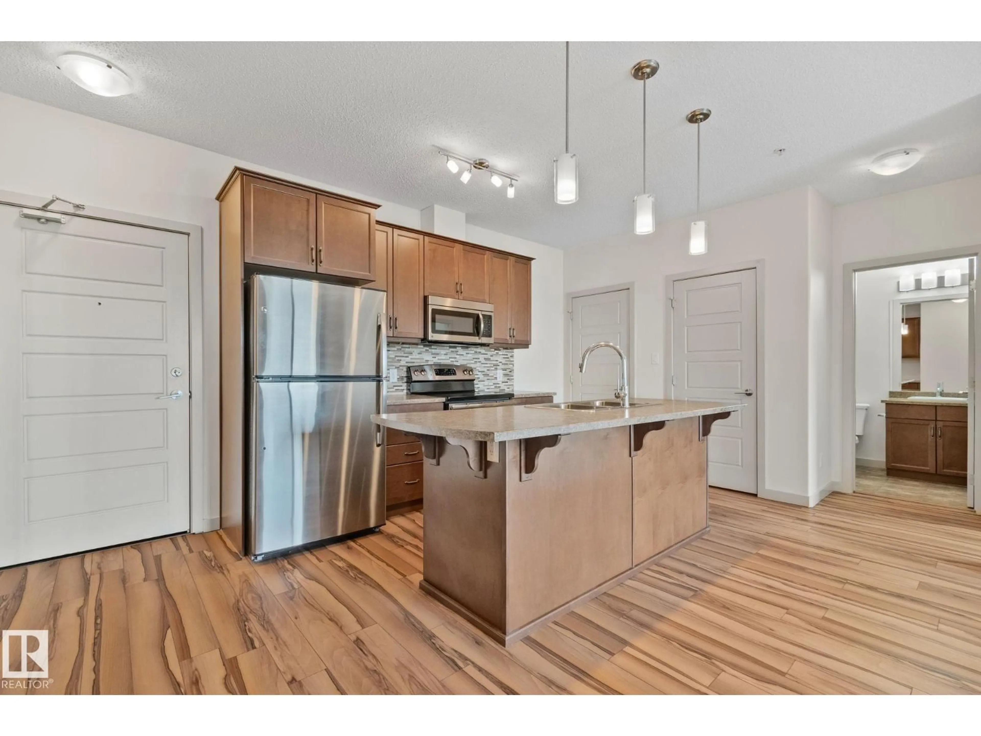 Open concept kitchen, wood/laminate floor for #218 - 320 AMBLESIDE LI, Edmonton Alberta T6W2Z9
