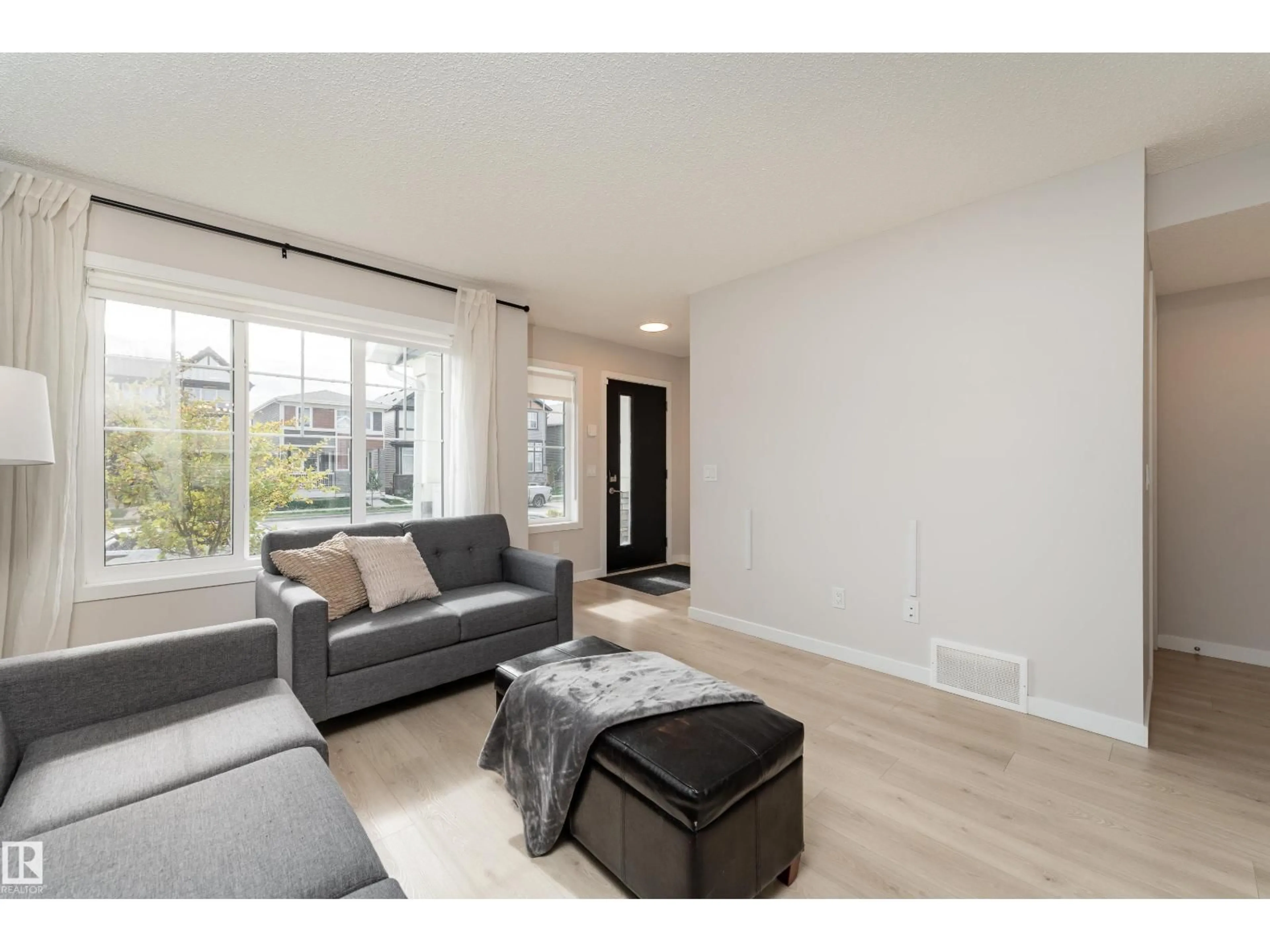 Living room with furniture, wood/laminate floor for 2420 TRUMPETER WY, Edmonton Alberta T5S0R9