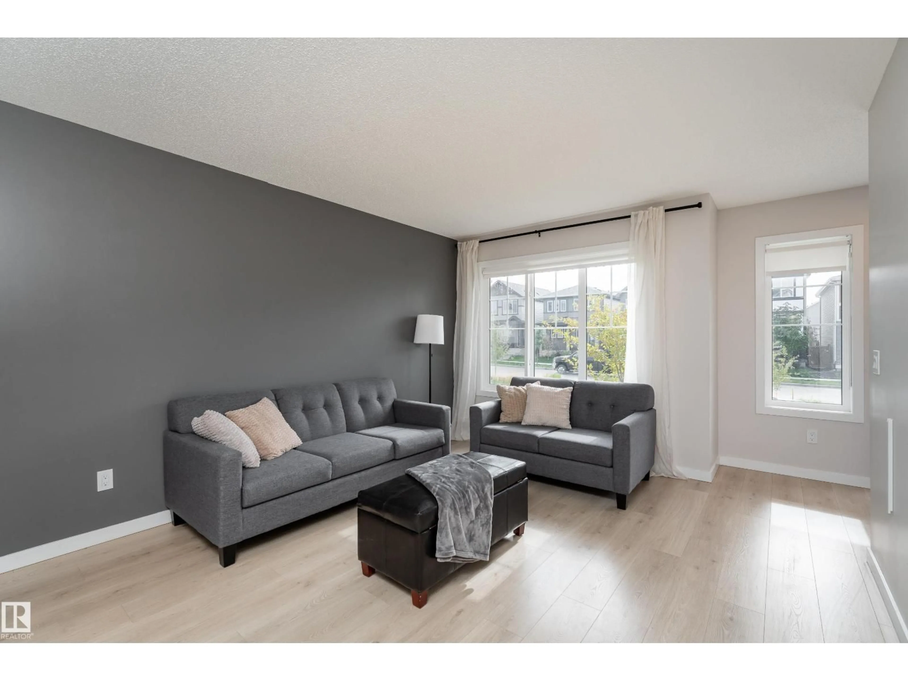Living room with furniture, wood/laminate floor for 2420 TRUMPETER WY, Edmonton Alberta T5S0R9