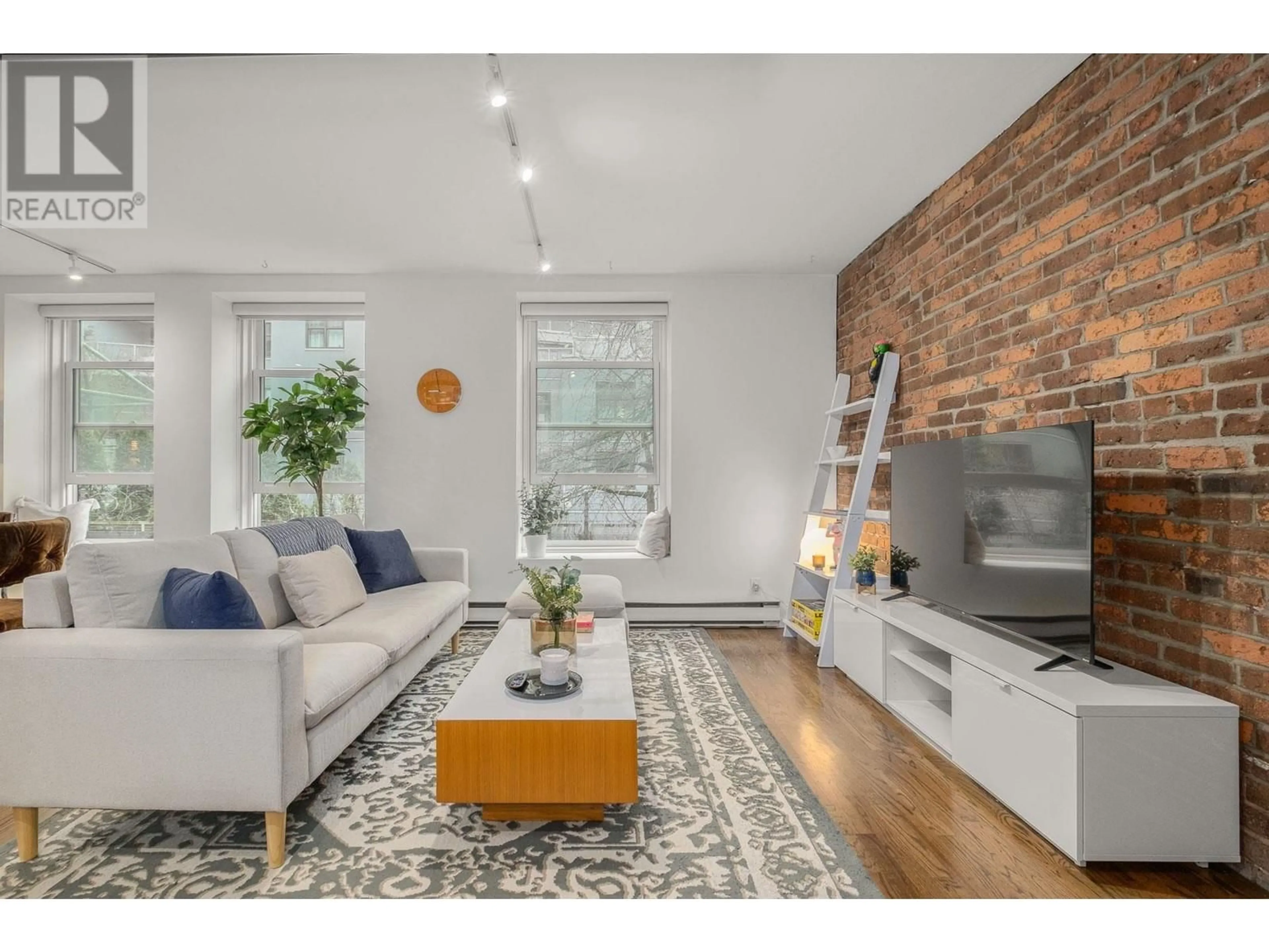 Living room with furniture, wood/laminate floor for 203 150 ALEXANDER STREET, Vancouver British Columbia V6A1B5