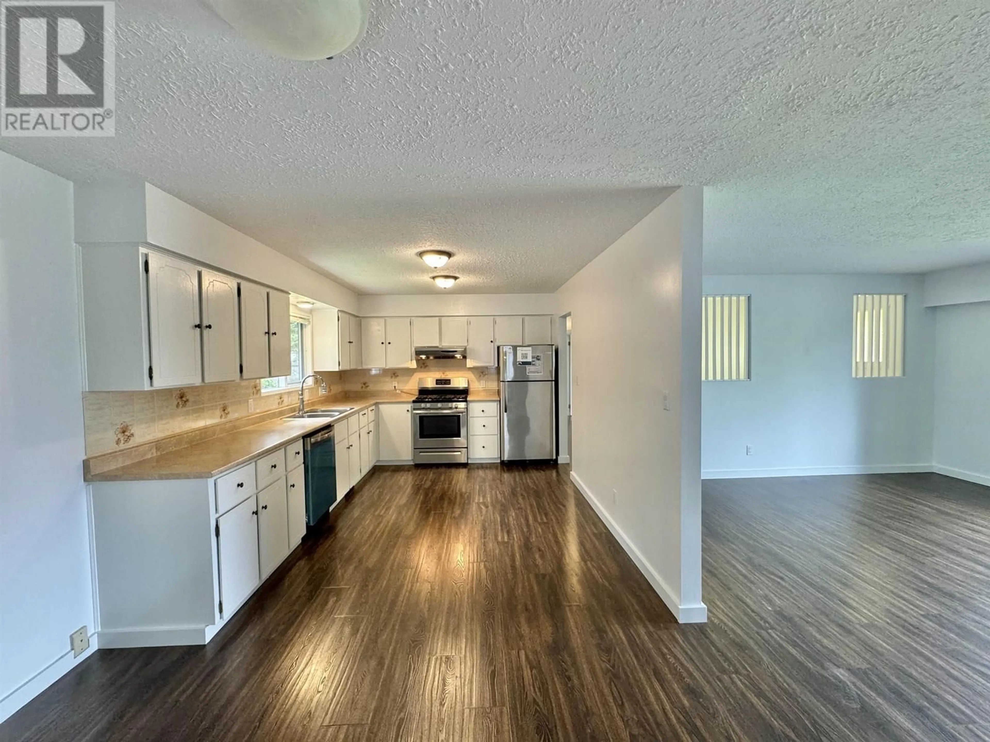 Open concept kitchen, wood/laminate floor for 721 CARIBOO TRAIL, 100 Mile House British Columbia V0K2E1