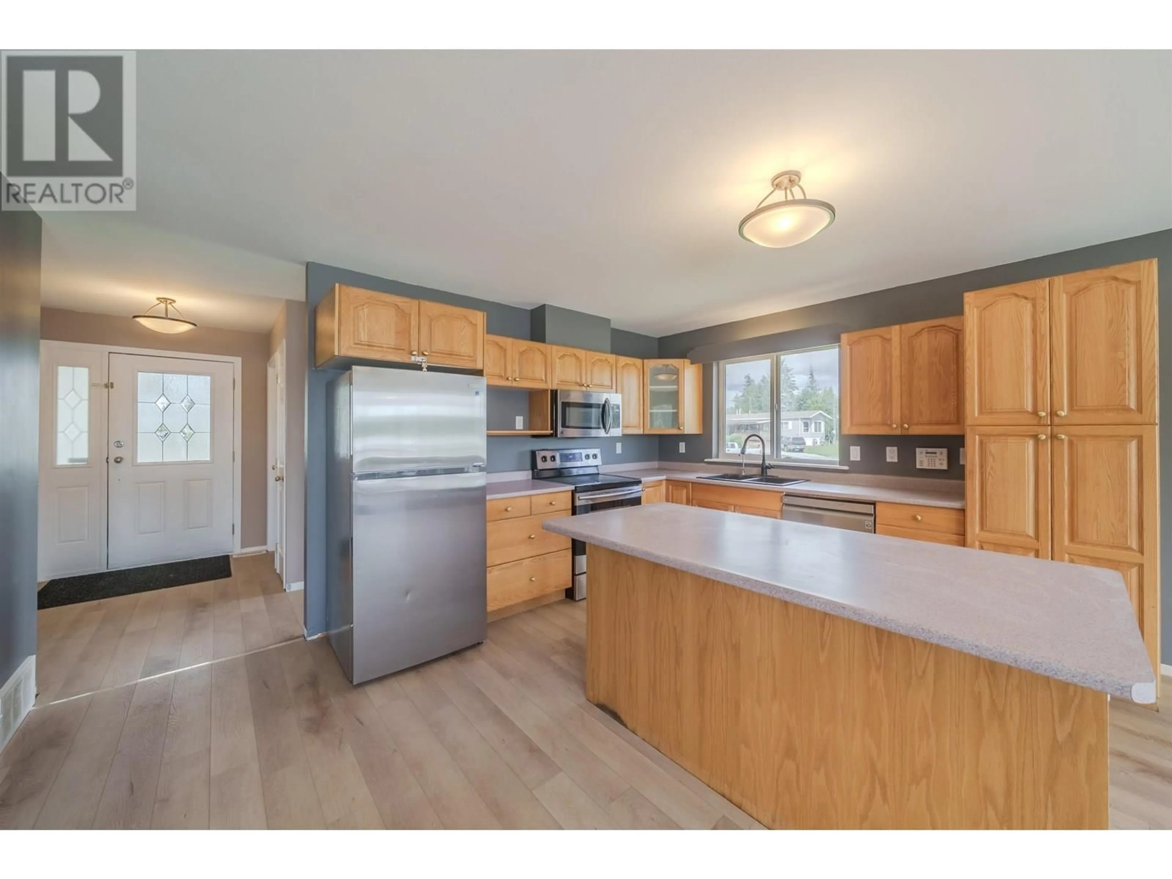 Open concept kitchen, wood/laminate floor for 5526 LAKESIDE COURT, 103 Mile House British Columbia V0K2E1