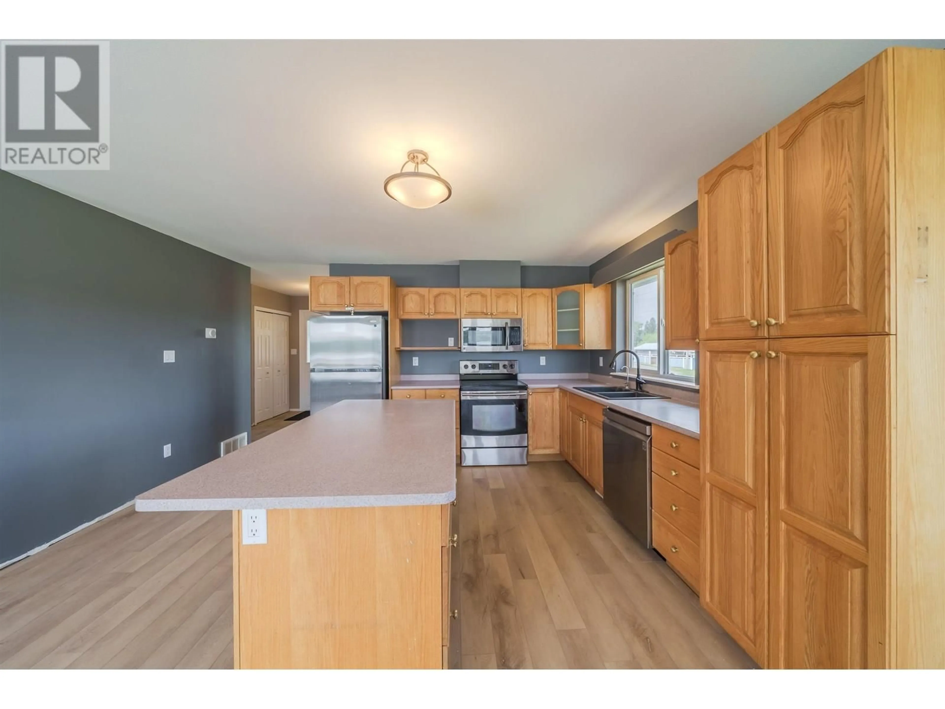 Open concept kitchen, wood/laminate floor for 5526 LAKESIDE COURT, 103 Mile House British Columbia V0K2E1