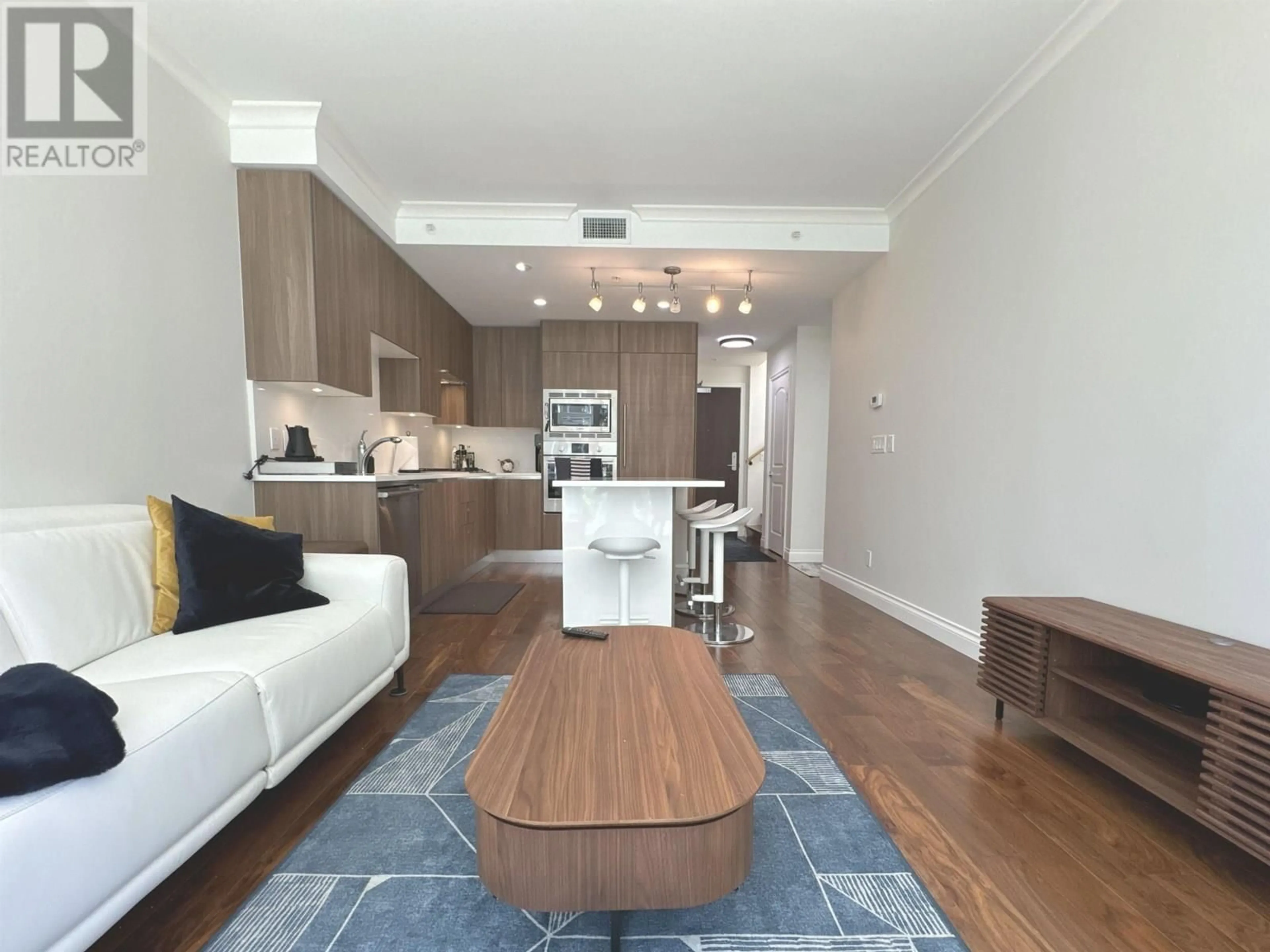 Living room with furniture, wood/laminate floor for 202 - 185 VICTORY SHIP WAY, Vancouver British Columbia V7L0G2