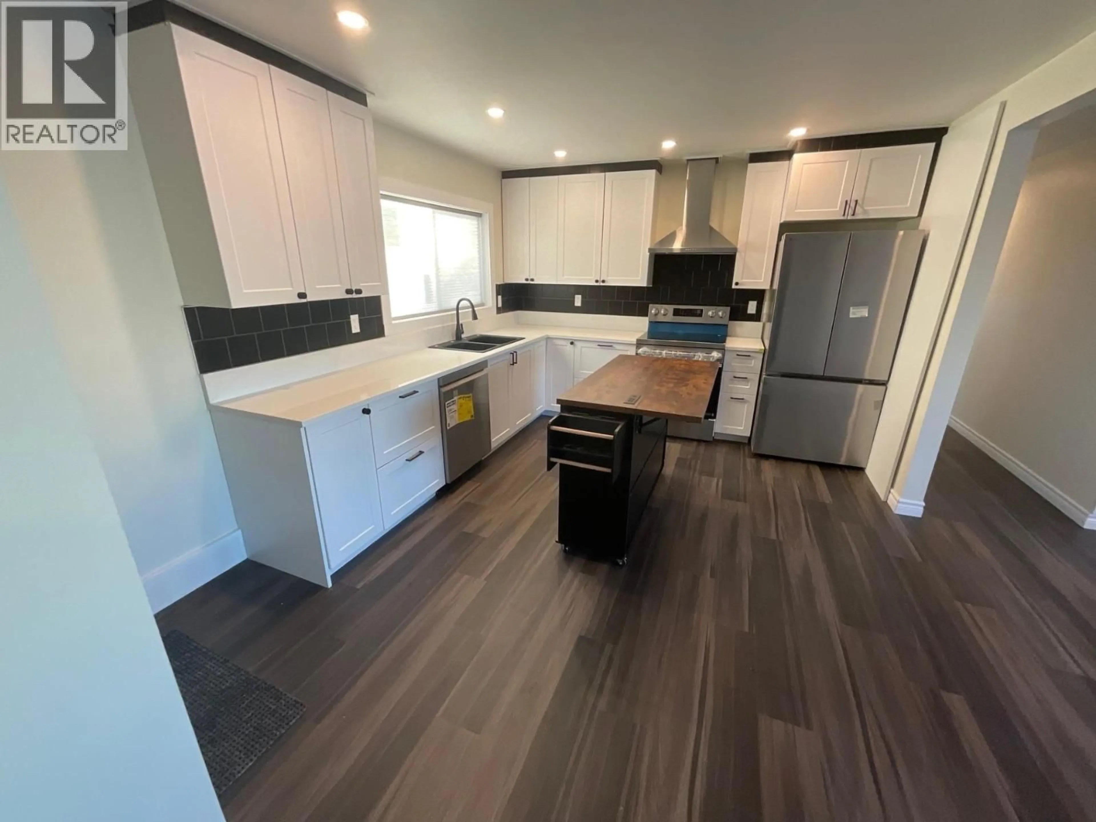 Open concept kitchen, wood/laminate floor for 8835 103 AVENUE, Fort St. John British Columbia V1J6P1