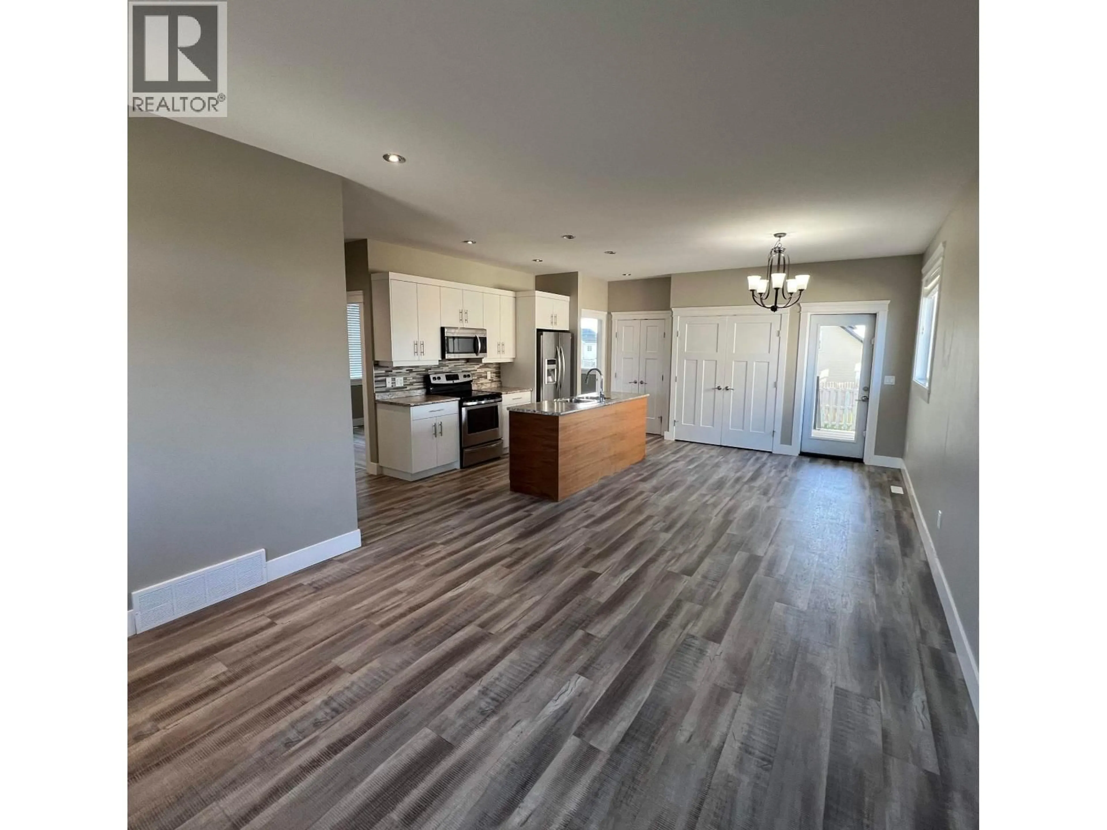 Open concept kitchen, wood/laminate floor for 8215 88 AVENUE, Fort St. John British Columbia V1J0N9