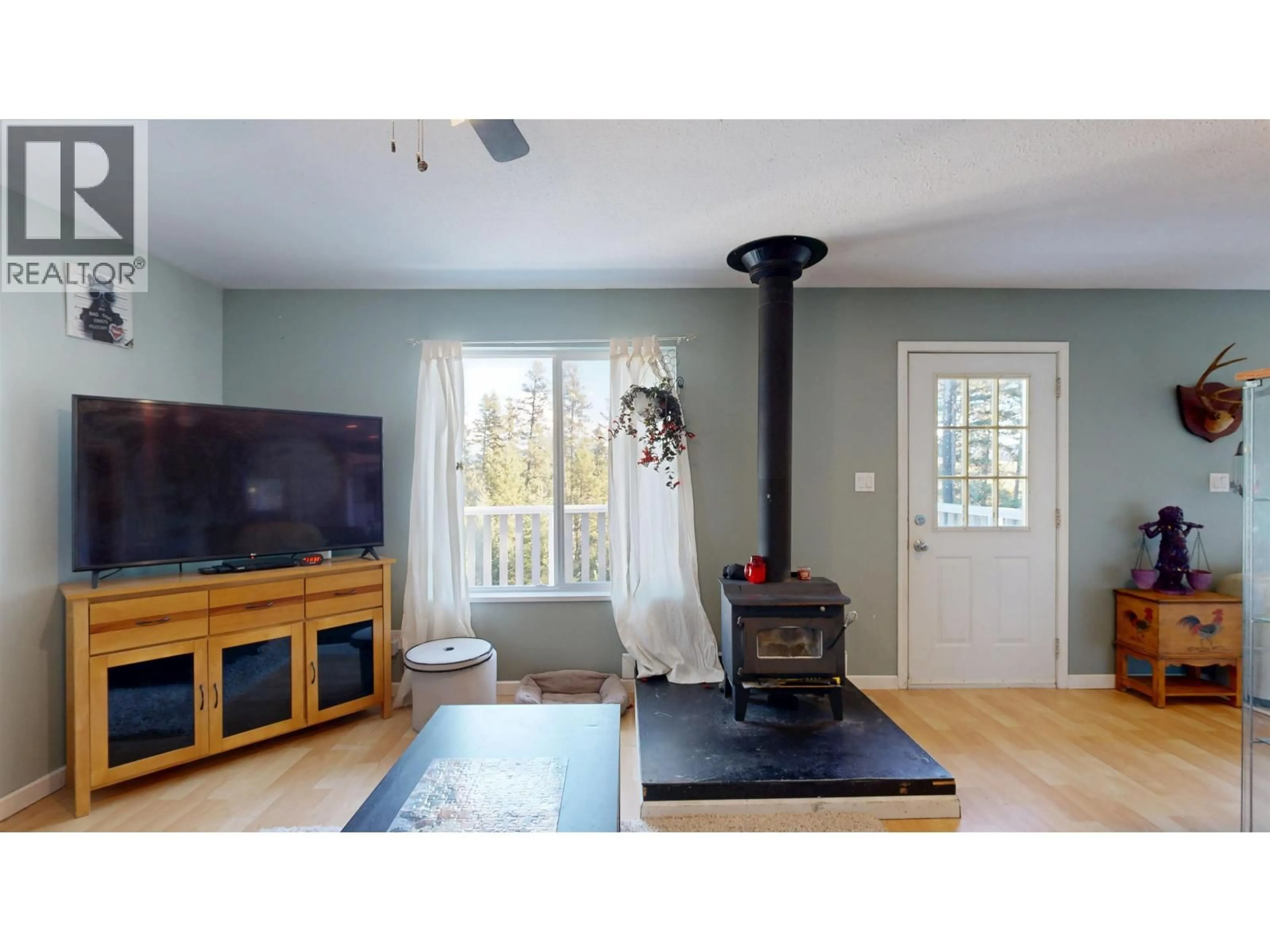 Living room with furniture, wood/laminate floor for 4871 STEWART ROAD, 100 Mile House British Columbia V0K2Z0