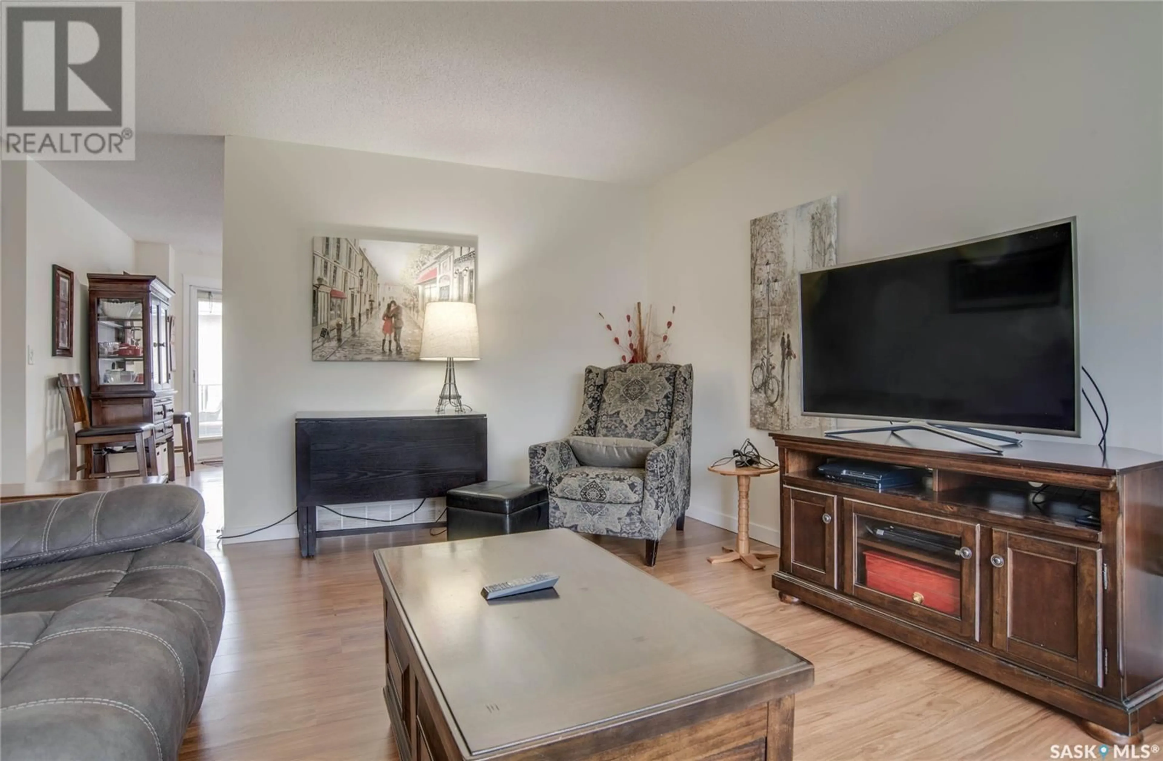 Living room with furniture, wood/laminate floor for 306 - 610 PEREHUDOFF CRESCENT, Saskatoon Saskatchewan S7H4H5