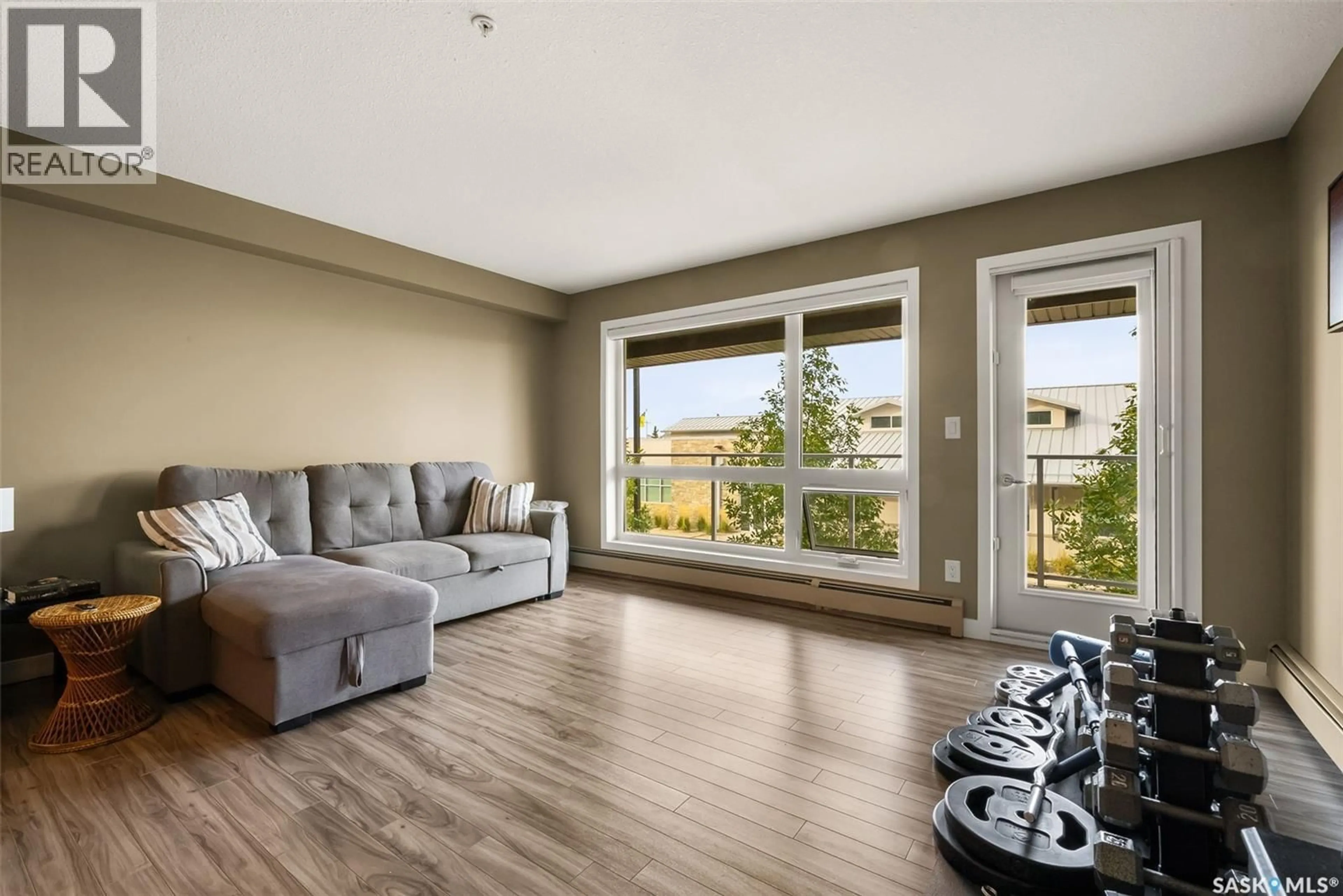 Living room with furniture, wood/laminate floor for 107 - 2311 WINDSOR PARK ROAD, Regina Saskatchewan S4V1S2