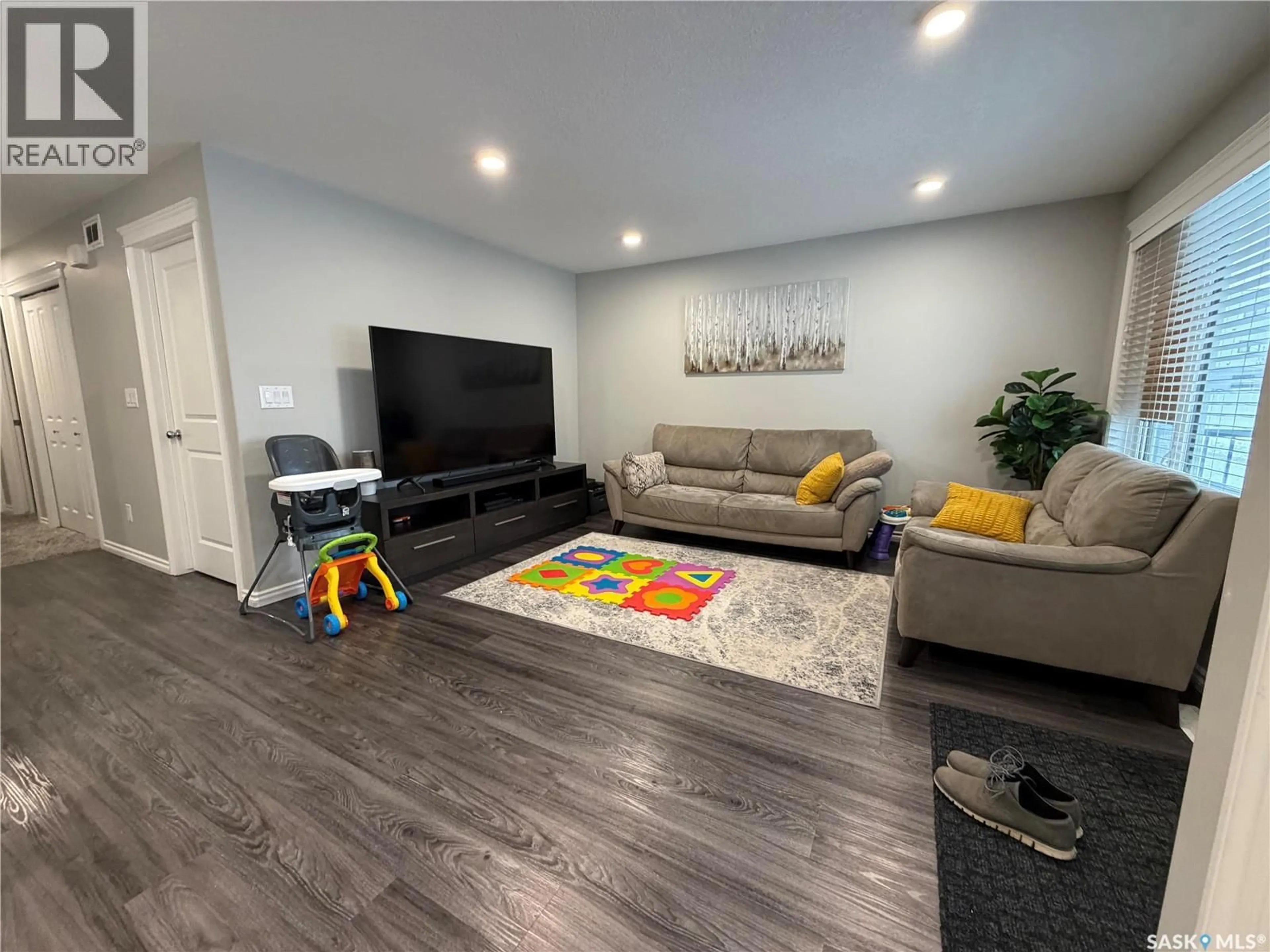 Living room with furniture, wood/laminate floor for 201 110 AKHTAR BEND, Saskatoon Saskatchewan S7W0Y9
