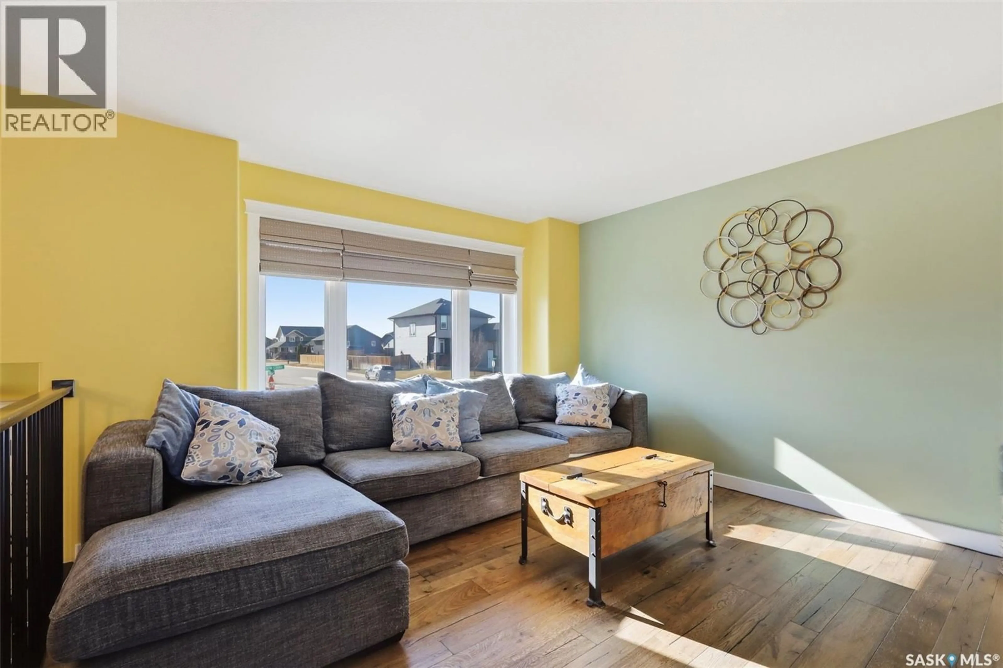 Living room with furniture, wood/laminate floor for 702 JANESON COURT, Warman Saskatchewan S0K4S2