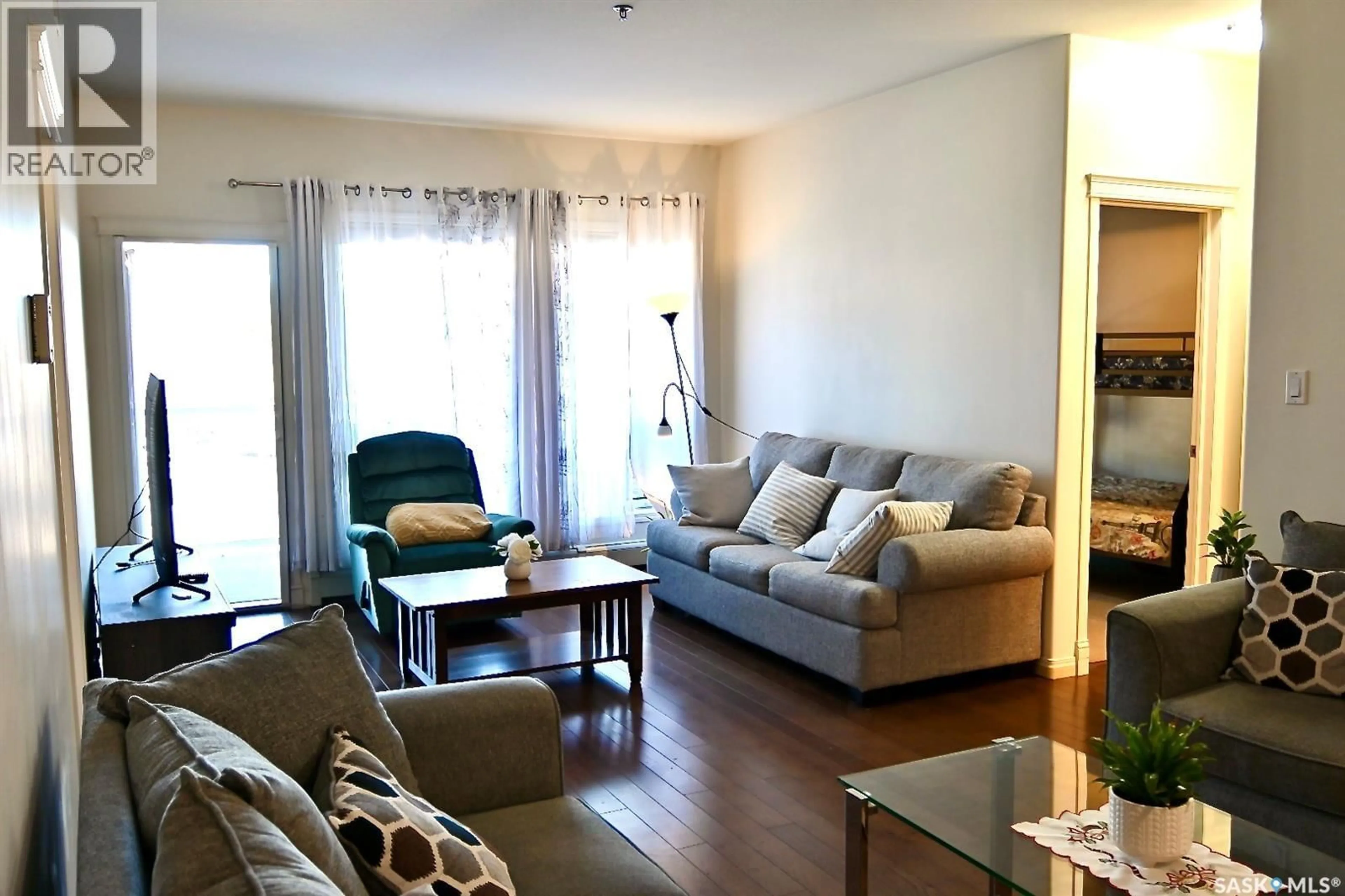 Living room with furniture, wood/laminate floor for 106 110 ARMISTICE WAY, Saskatoon Saskatchewan S7J5L8