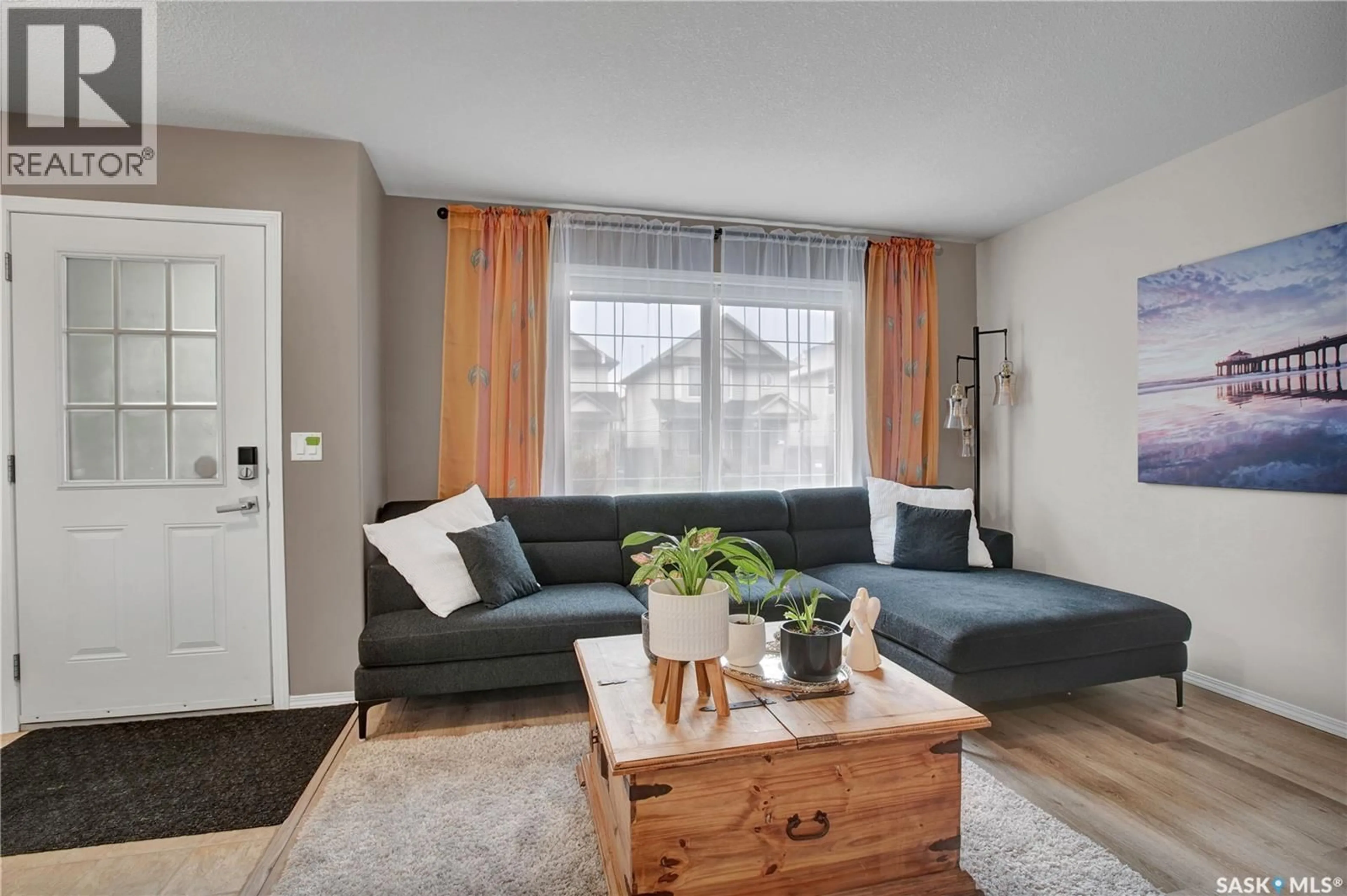 Living room with furniture, wood/laminate floor for 122 BLAKENEY CRESCENT, Saskatoon Saskatchewan S7L7N4