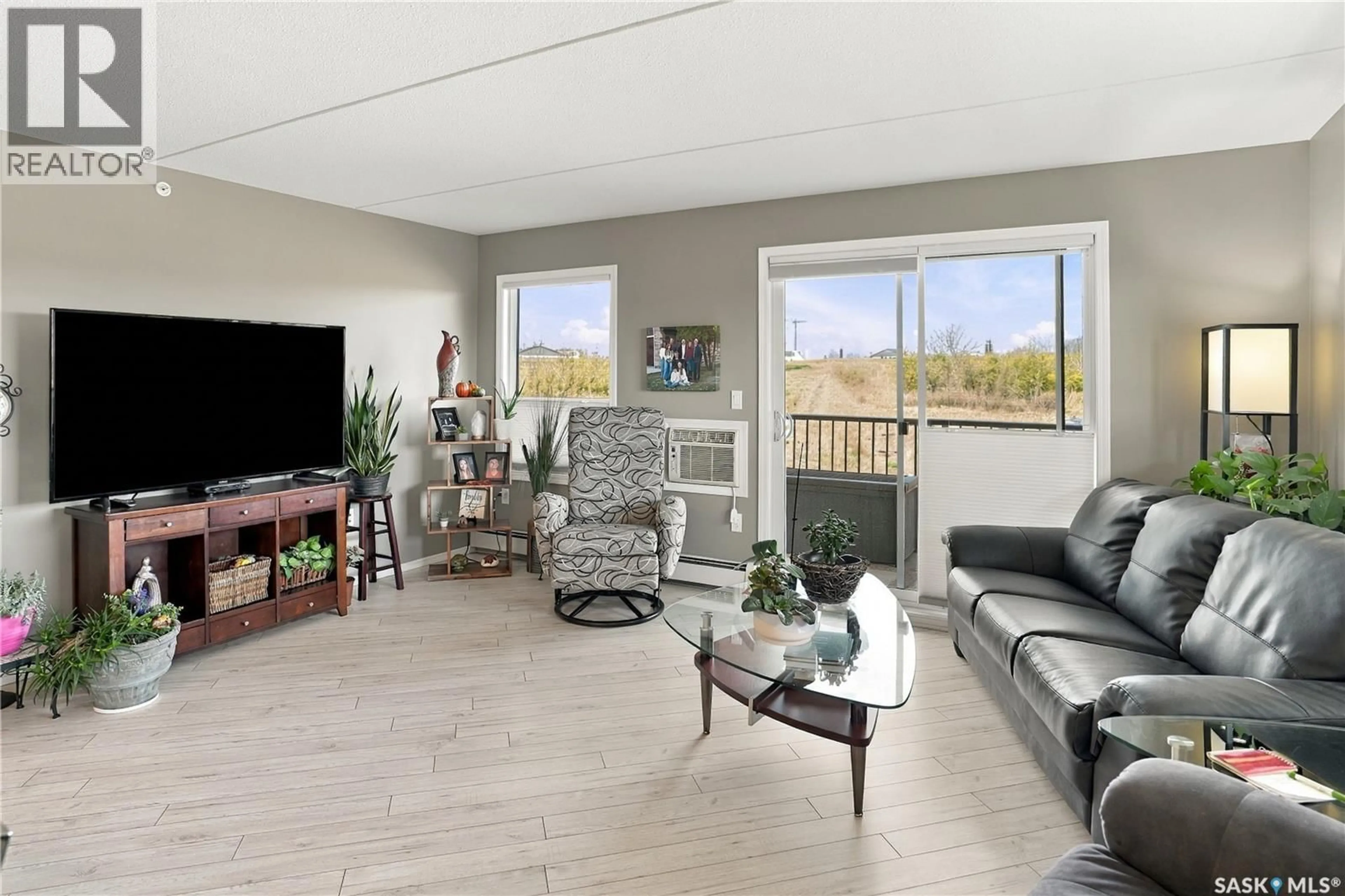 Living room with furniture, wood/laminate floor for 203 - 2426 BUHLER AVENUE, North Battleford Saskatchewan S9A1R5